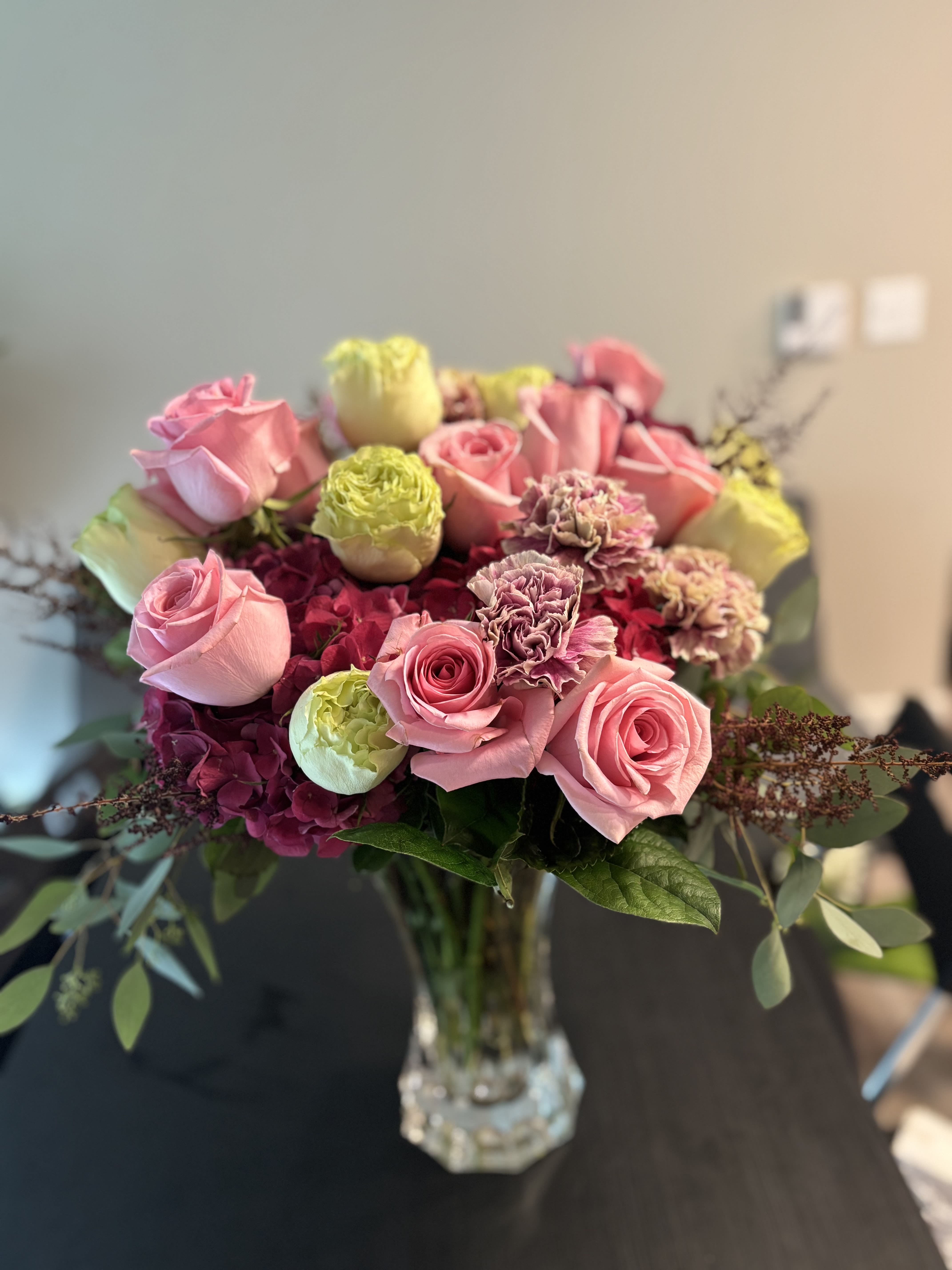 Pink roses and carnations arranged in a clear glass vase