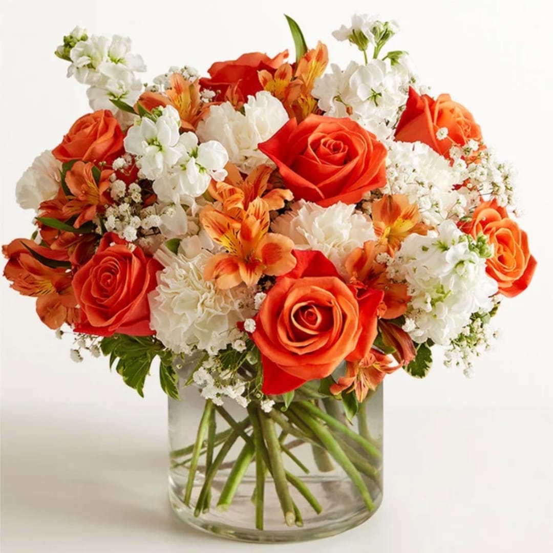 Orange and white flower bouquet in a clear glass vase