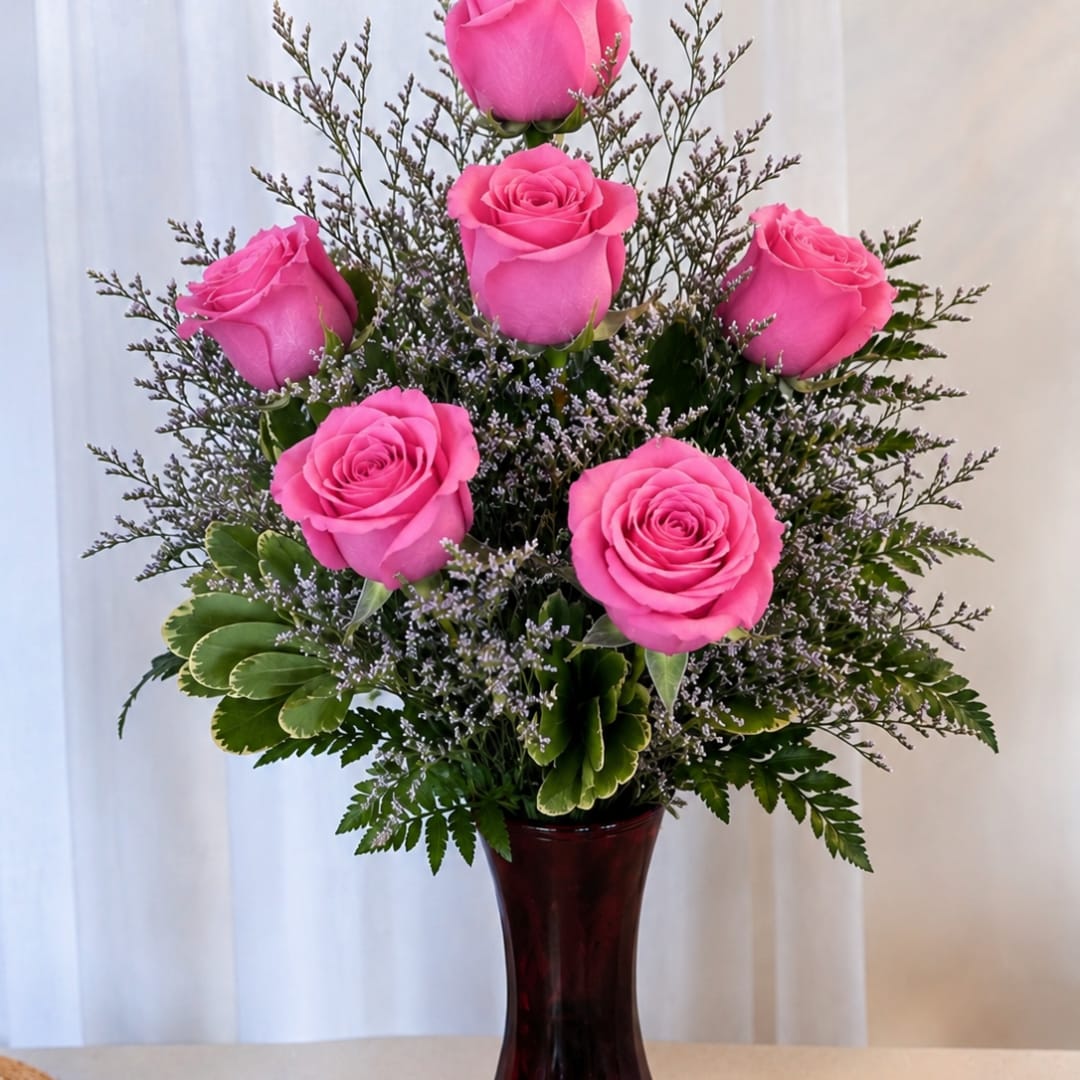 Pink roses arranged in a dark vase with greenery