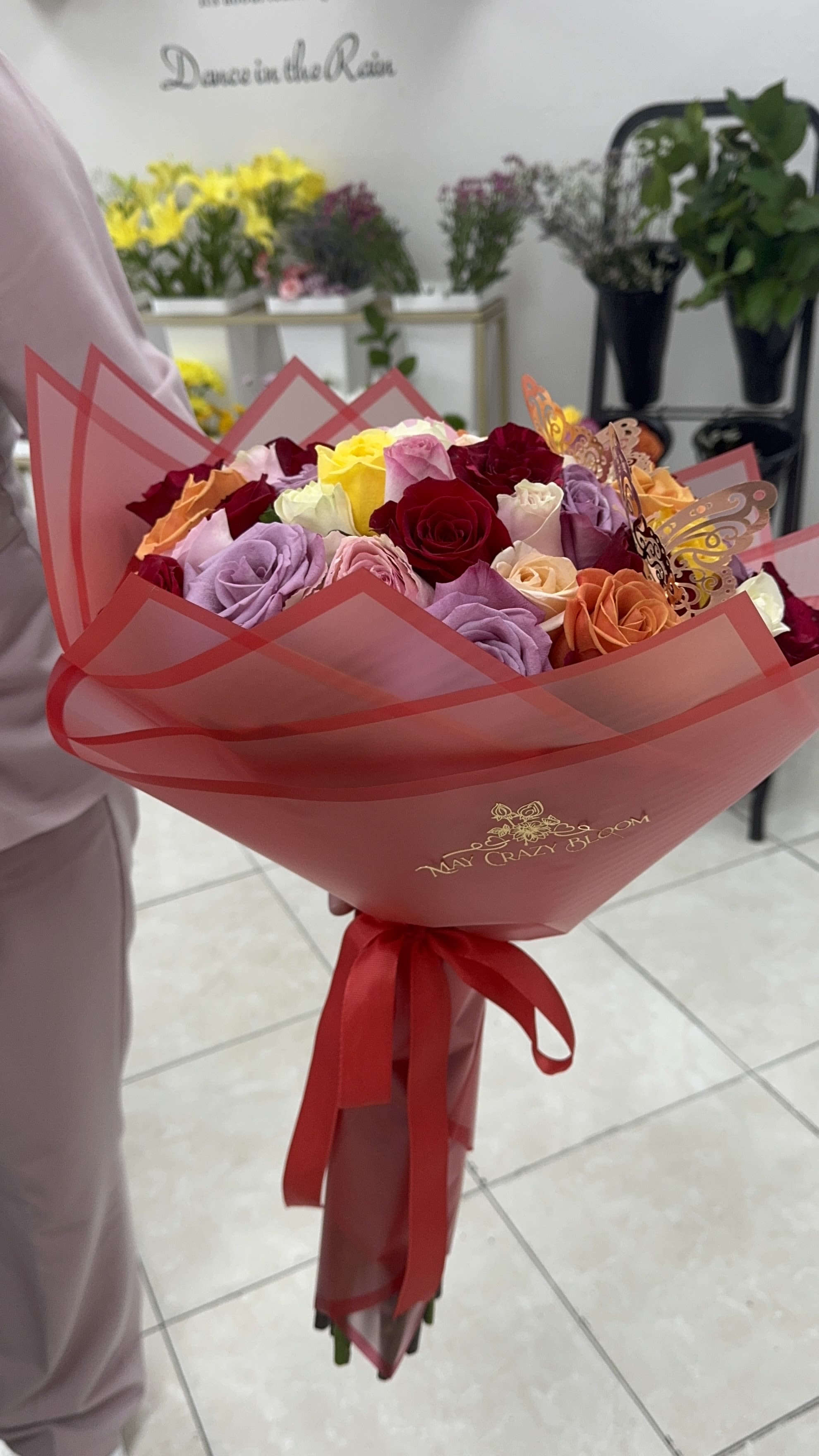 Bouquet of multicolored roses wrapped in pink paper with a red ribbon