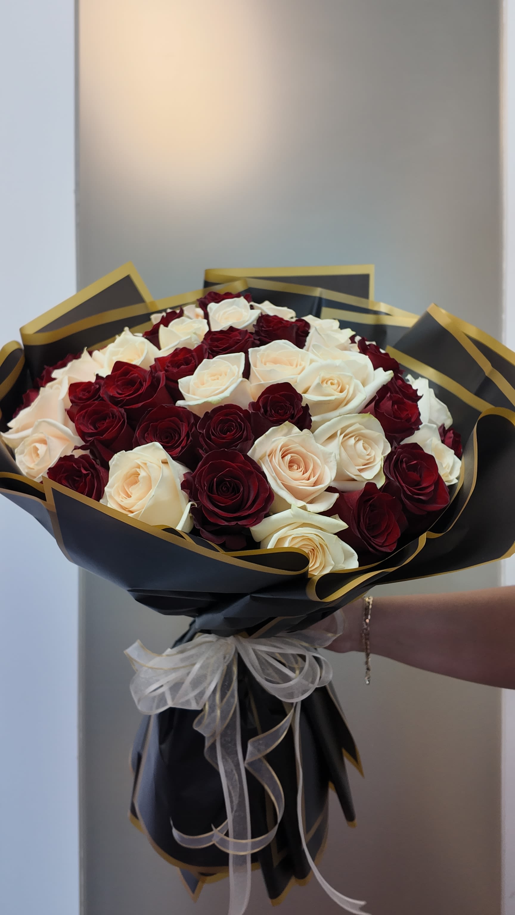 Bouquet of red and white roses wrapped in black paper with gold trim
