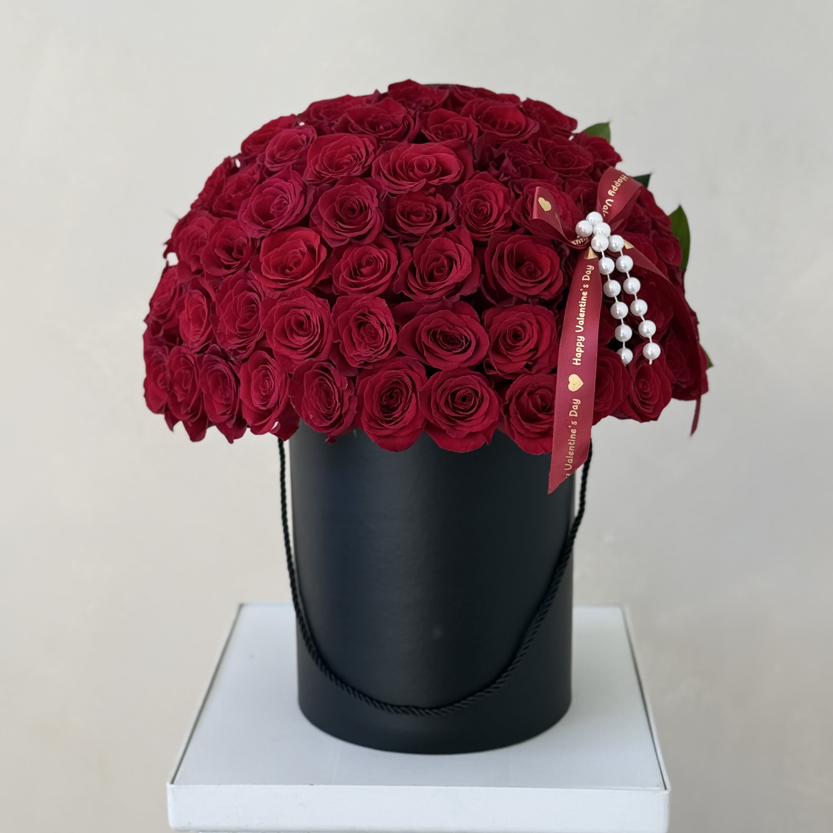 Red rose bouquet in a black hatbox with a Valentine ribbon