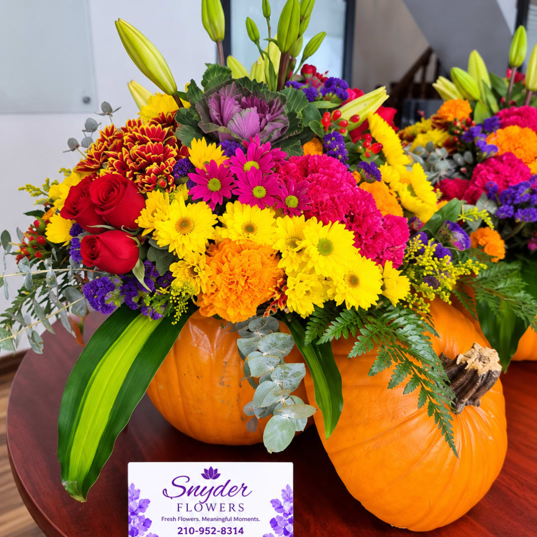Colorful mixed flower arrangement in pumpkins with a business card in front