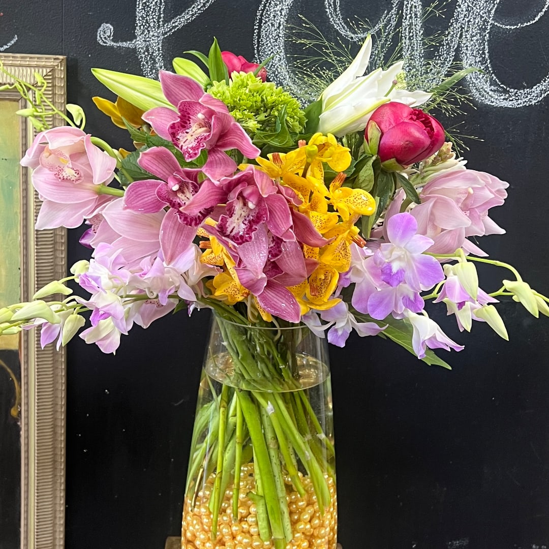 Mixed bouquet of orchids and lilies in a clear glass vase
