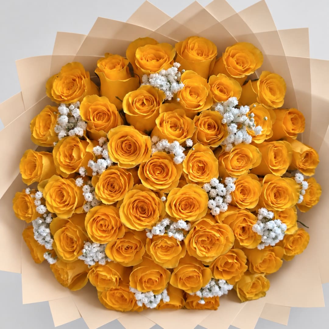 Bouquet of yellow roses with small white filler flowers wrapped in beige paper