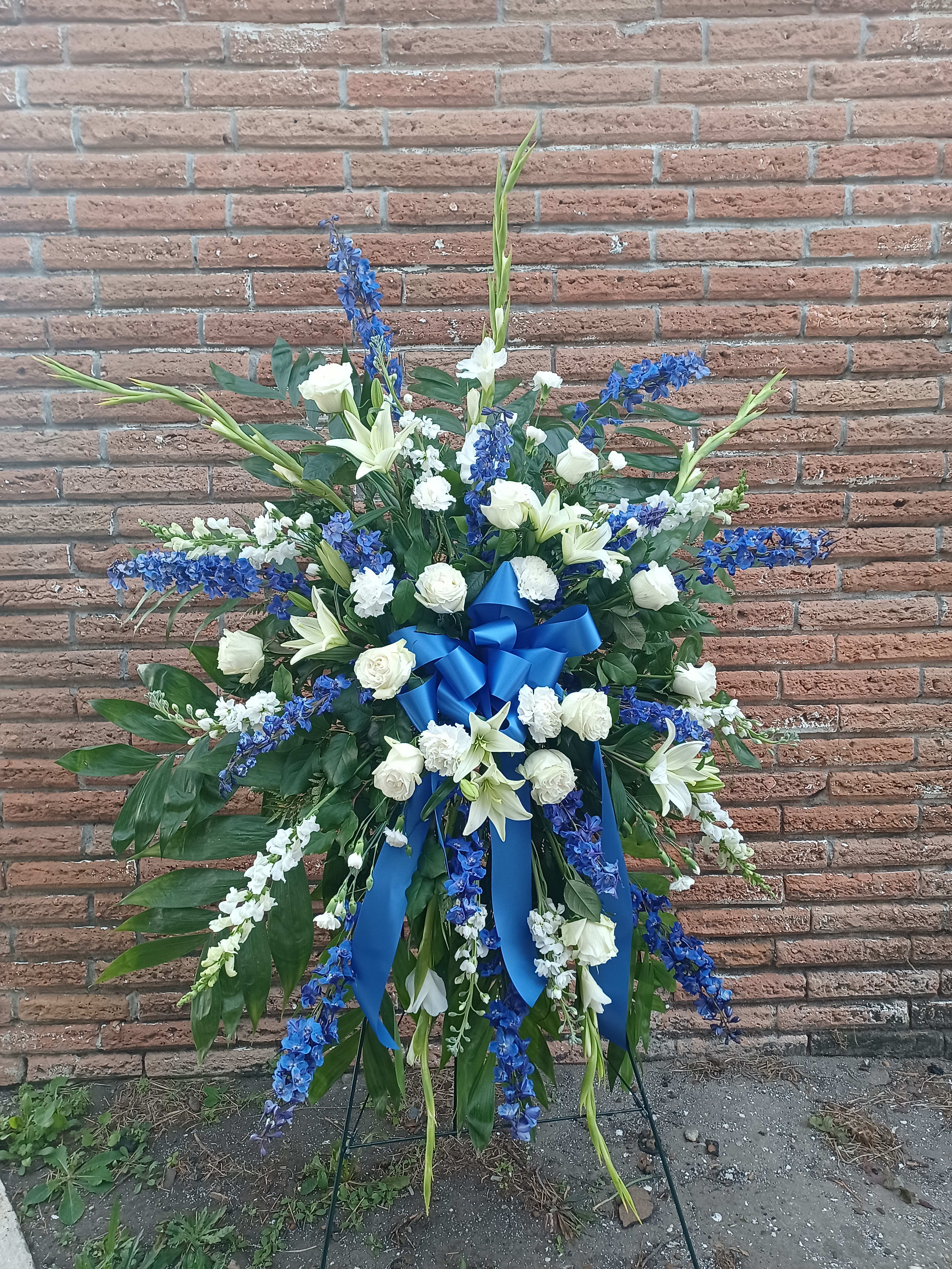 Large standing floral spray with white lilies, roses, and blue flowers