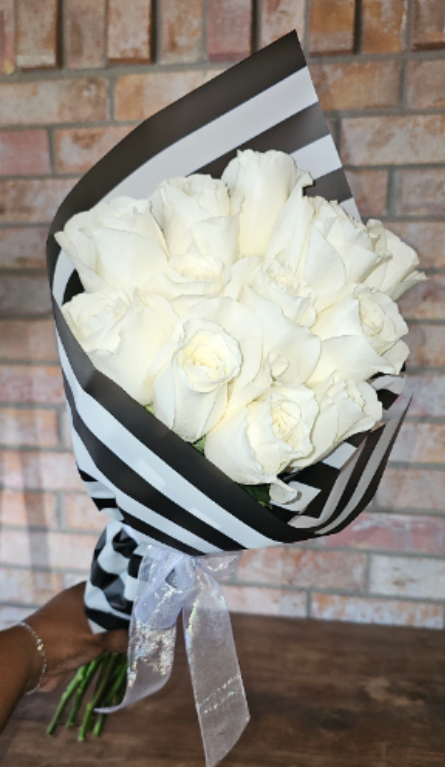 Ivory Luxe Rose Bouquet - A timeless bouquet of premium ivory roses wrapped in our signature black-and-white paper and finished with soft ribbon. Clean, classic, and effortlessly elegant — perfect for celebrations, sympathy, or refined everyday gifting.  Available in Dozen, 18-Stem, or Two Dozen options