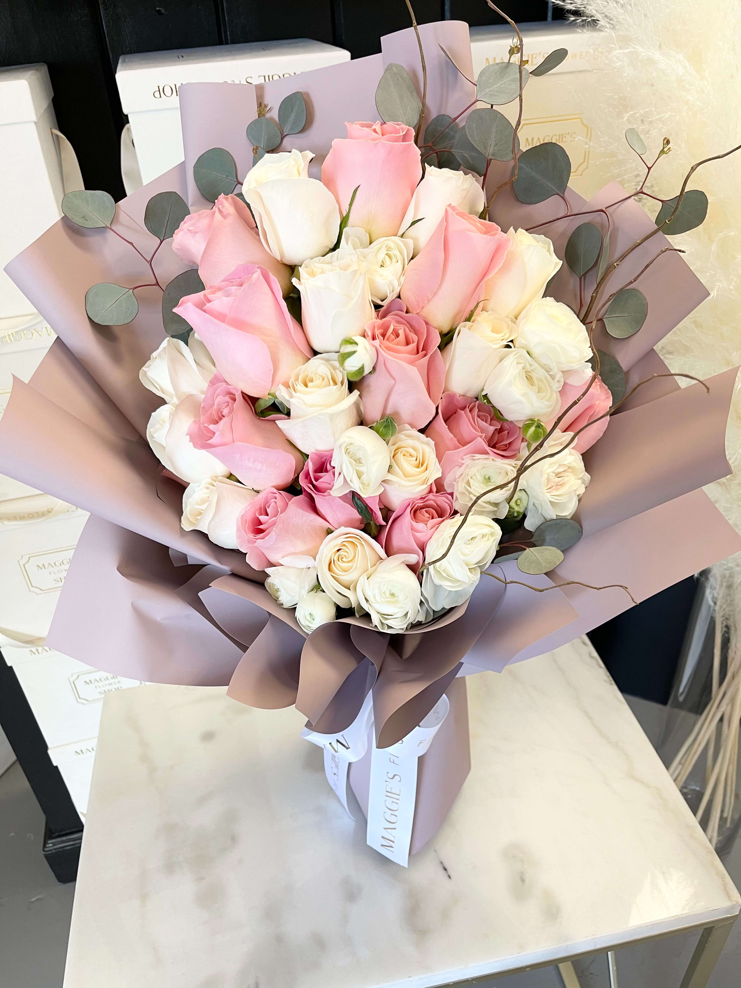 Bouquet of pink and white roses wrapped in mauve paper