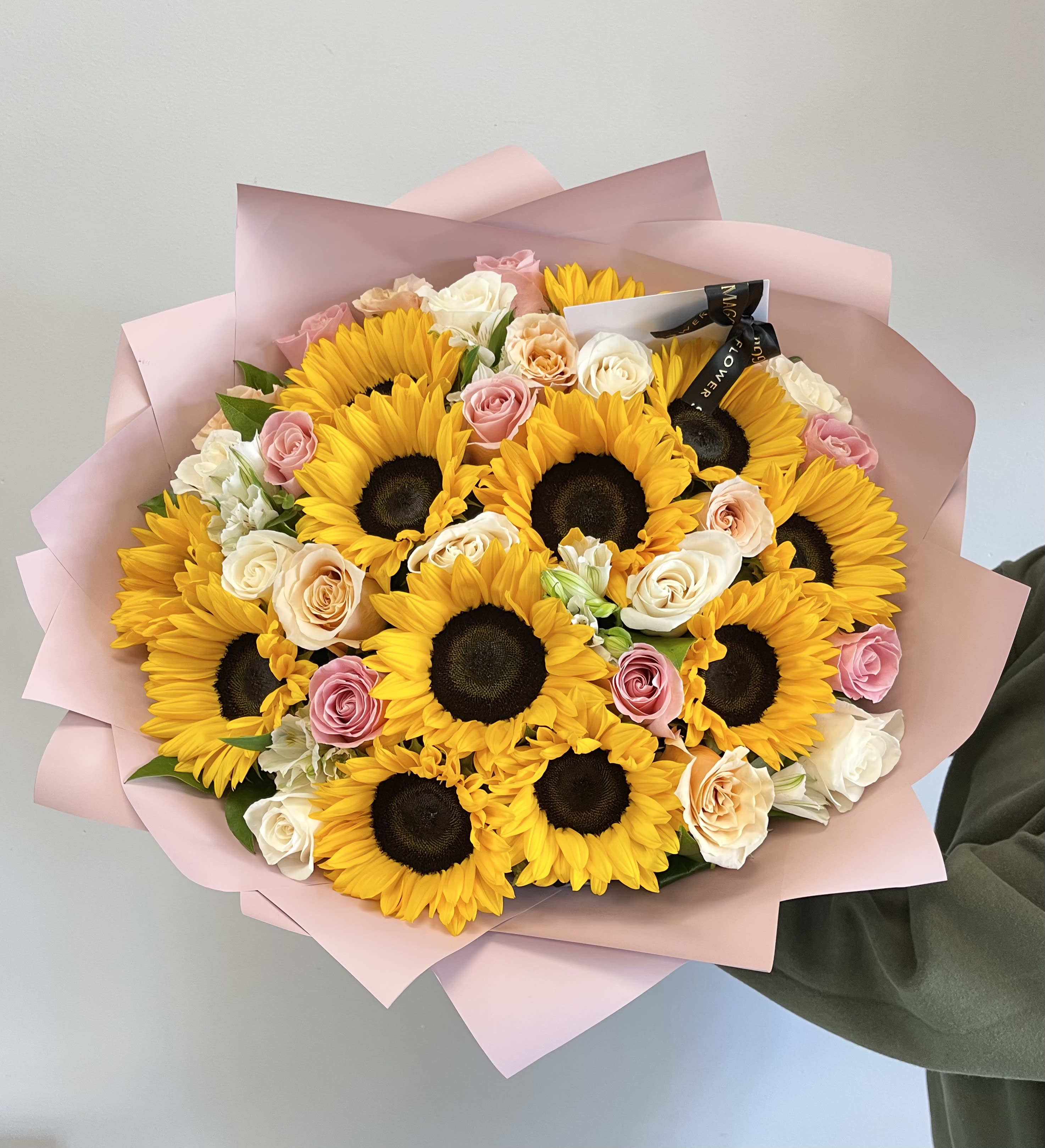 Bouquet of sunflowers and pastel roses wrapped in pink paper
