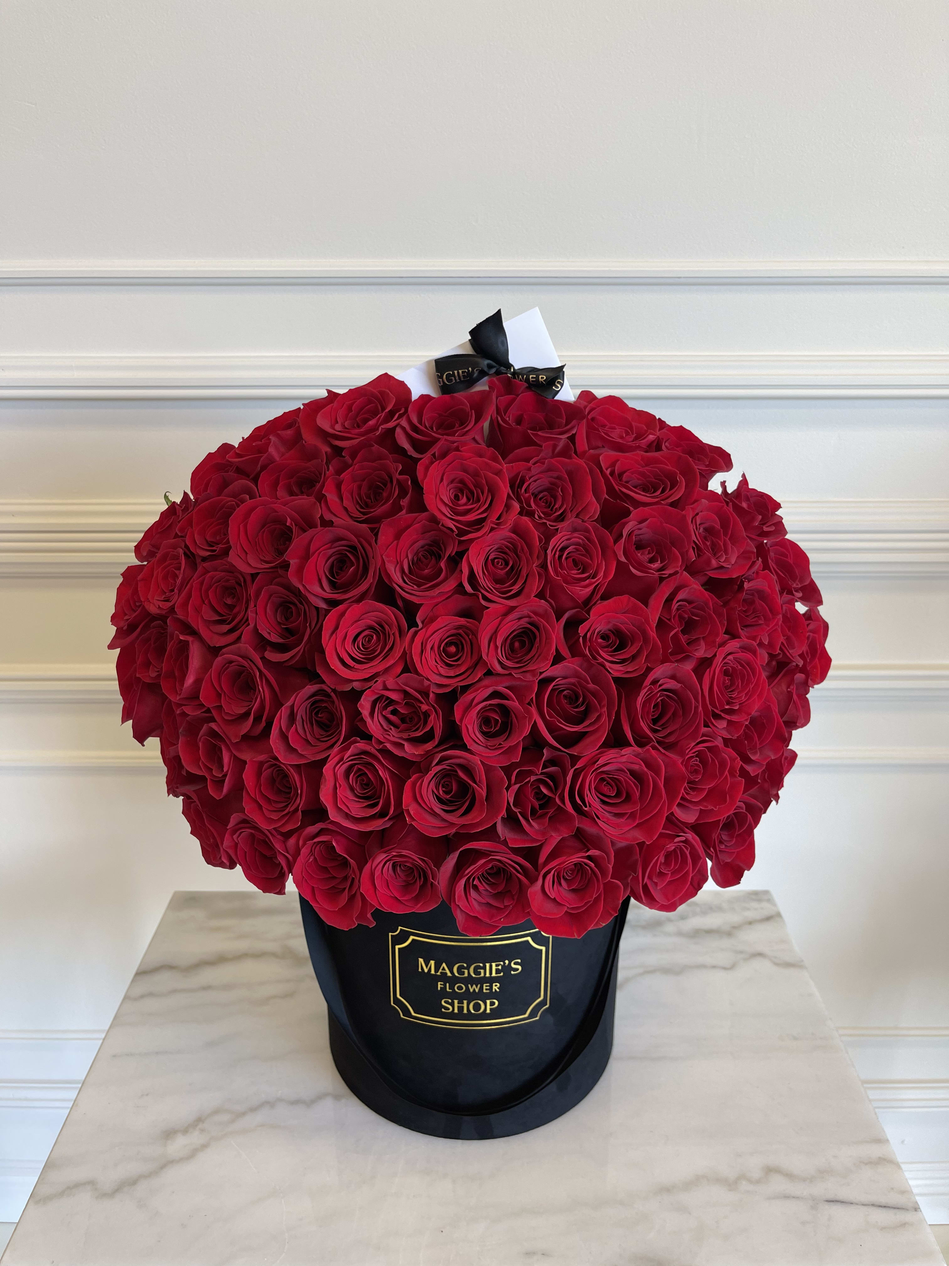 Large bouquet of red roses in a black hatbox
