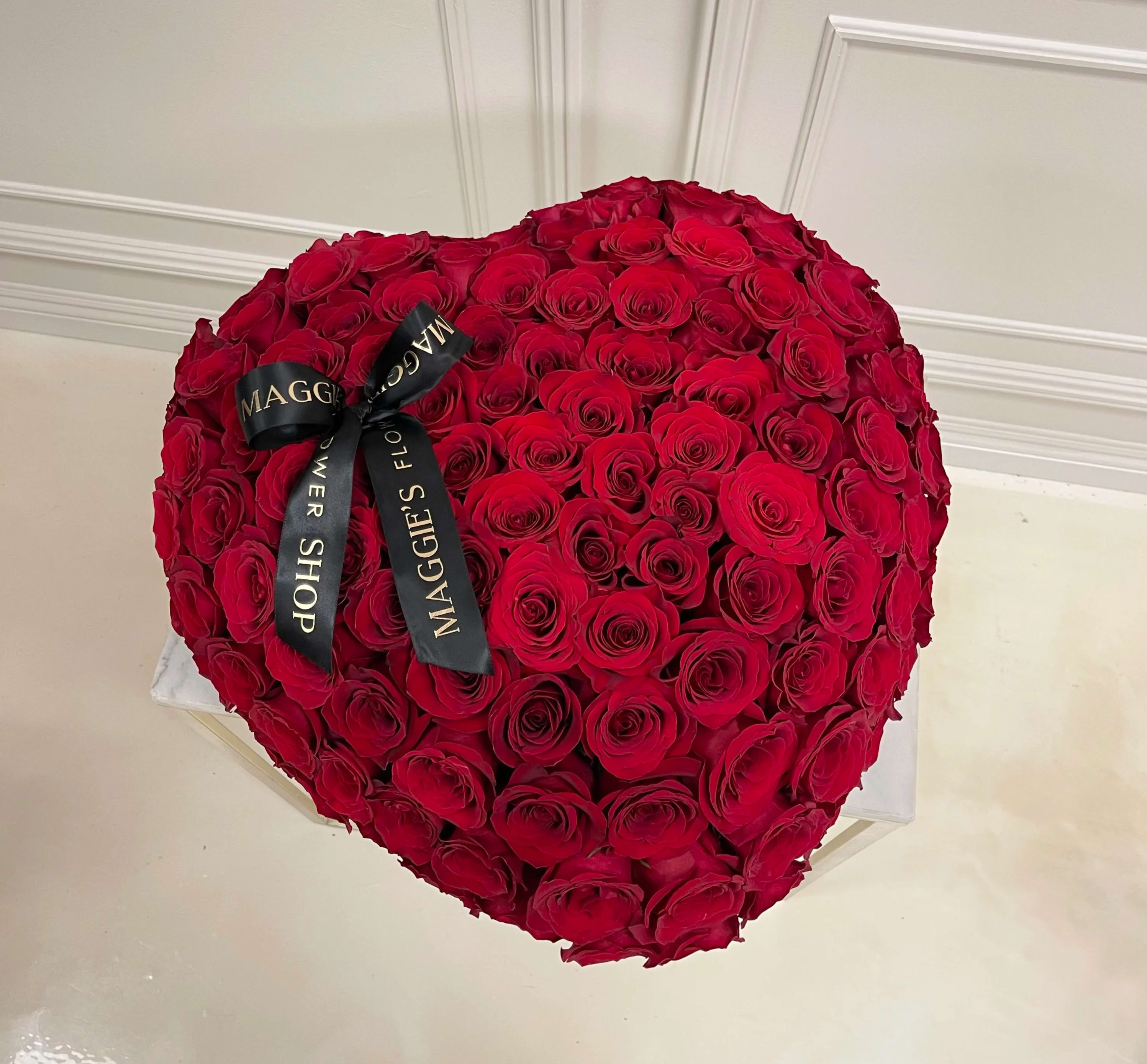 Heart-shaped bouquet of red roses with a black ribbon
