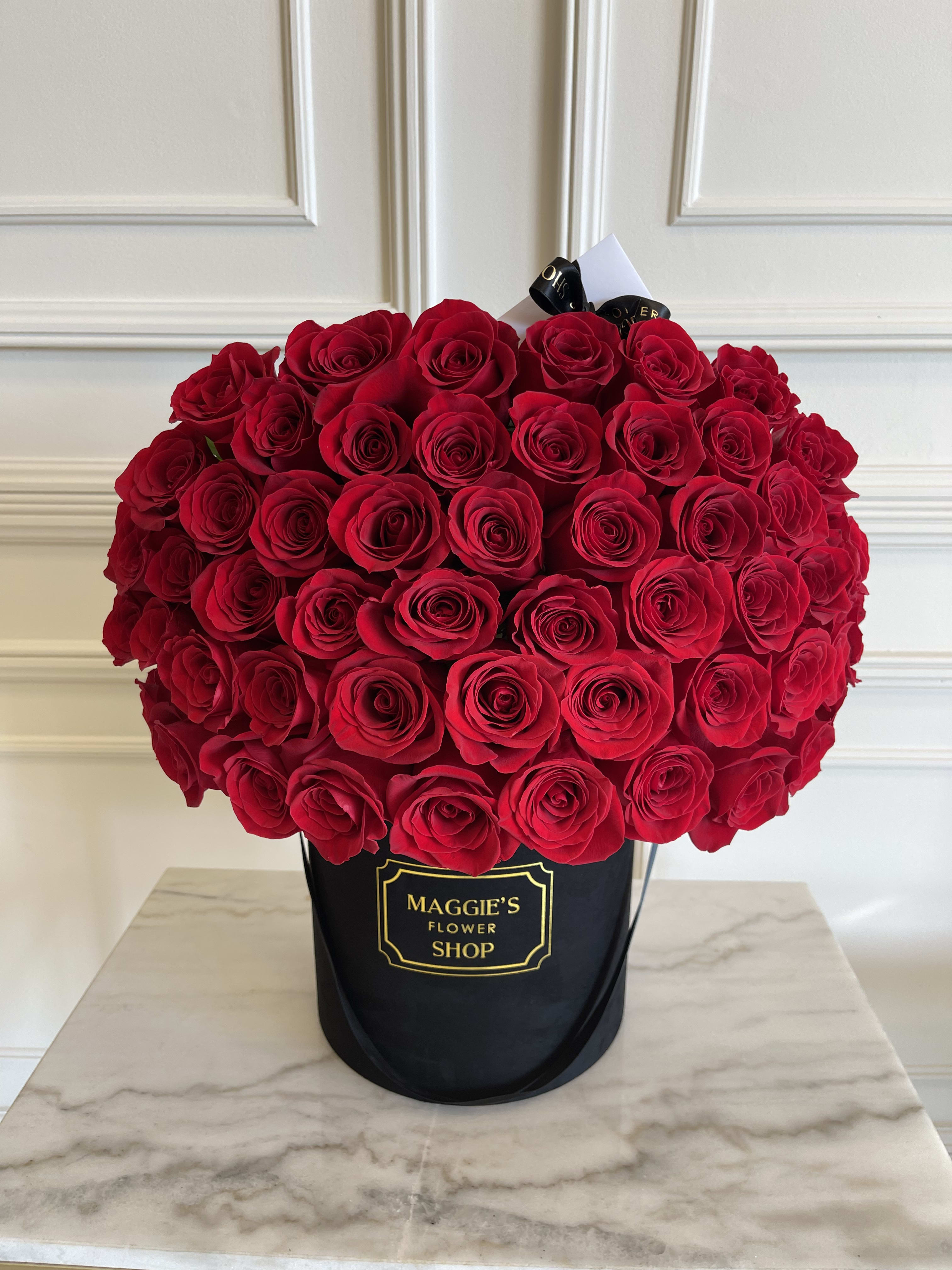 Large bouquet of red roses in a black hatbox