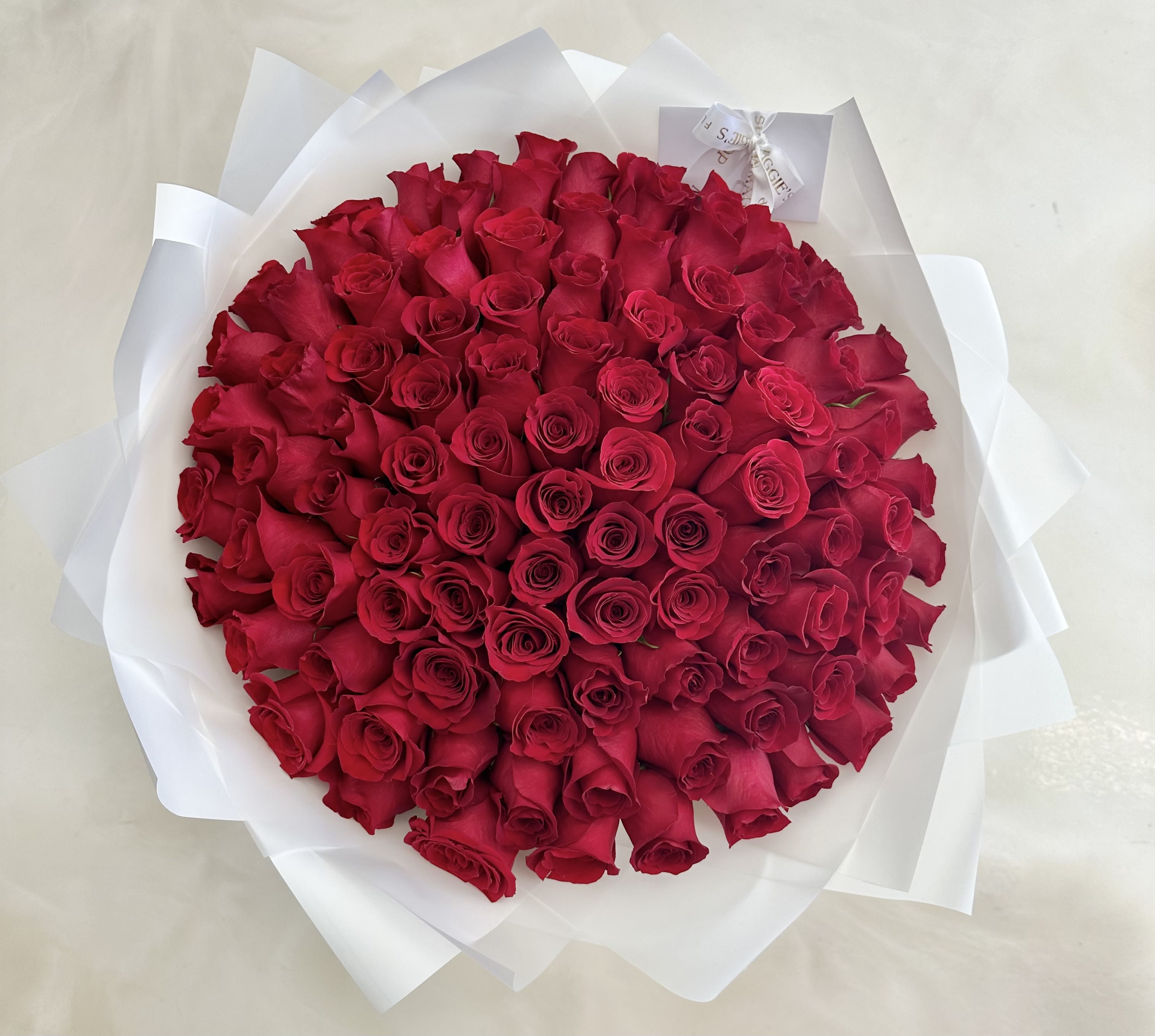 Round bouquet of red roses wrapped in white paper