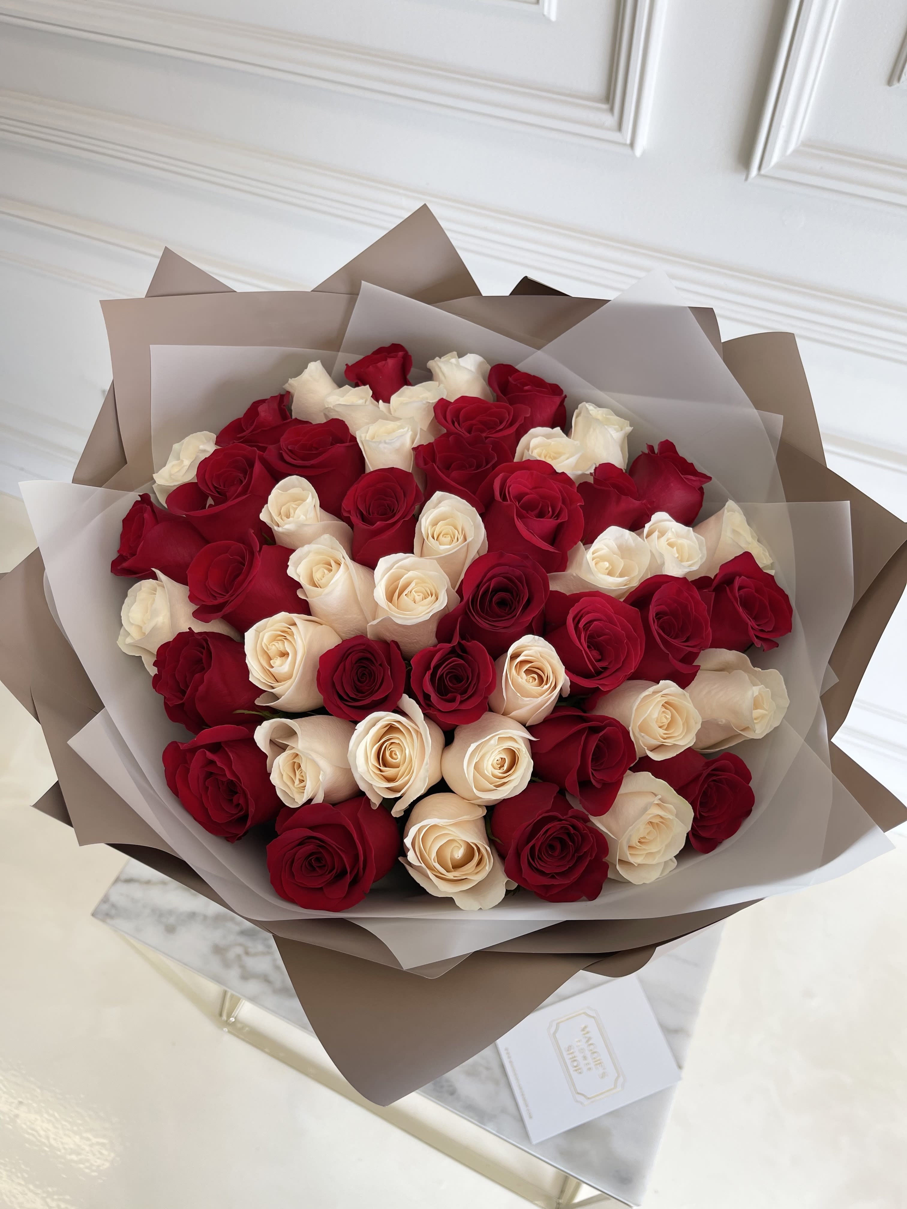 Bouquet of red and cream roses wrapped in brown and translucent paper