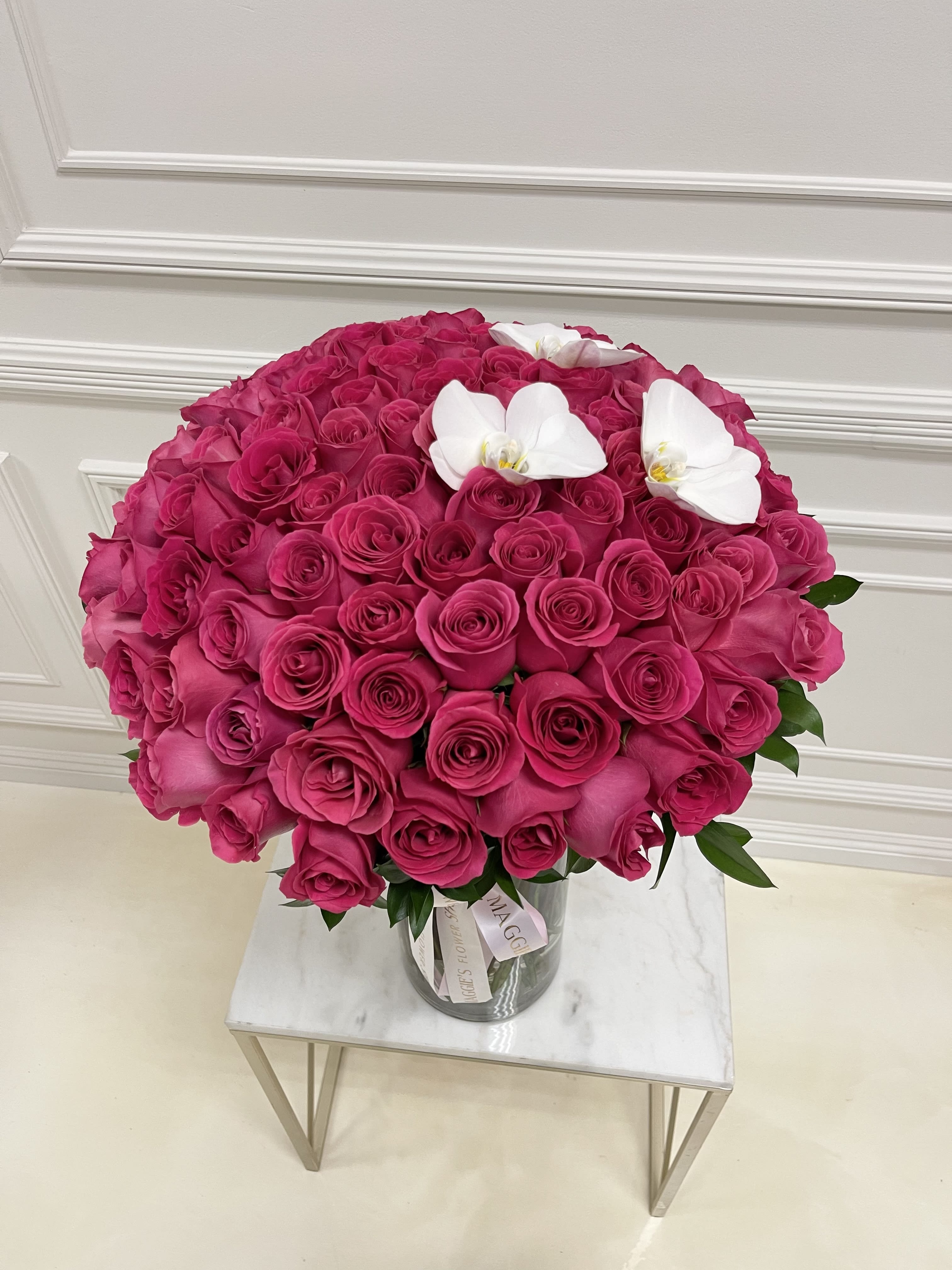 Large bouquet of hot pink roses with white orchids in a glass vase
