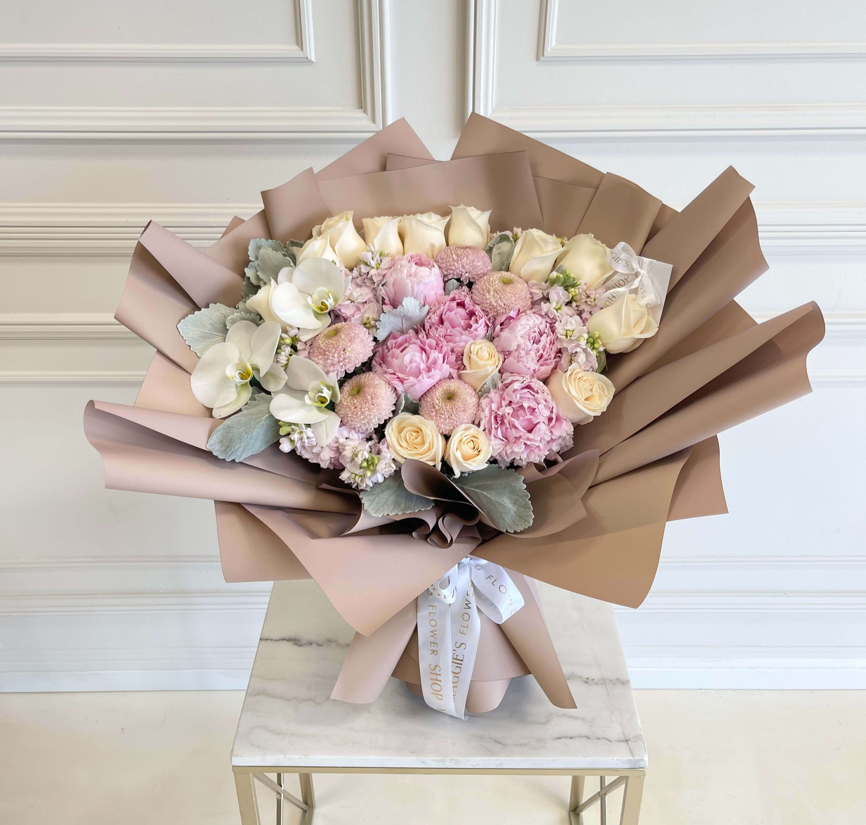 Bouquet of pink and cream flowers wrapped in tan paper
