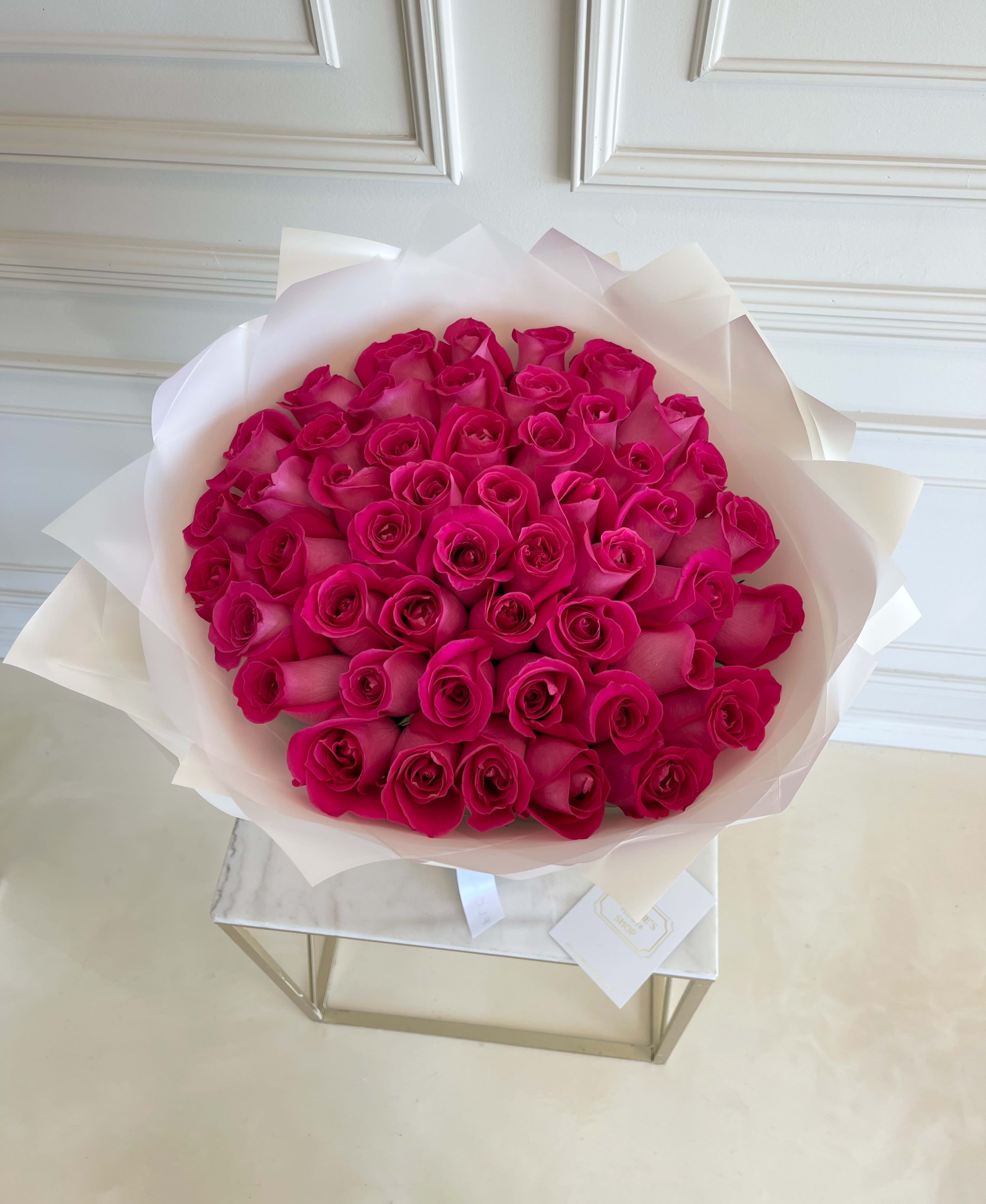 Bouquet of hot pink roses wrapped in white paper