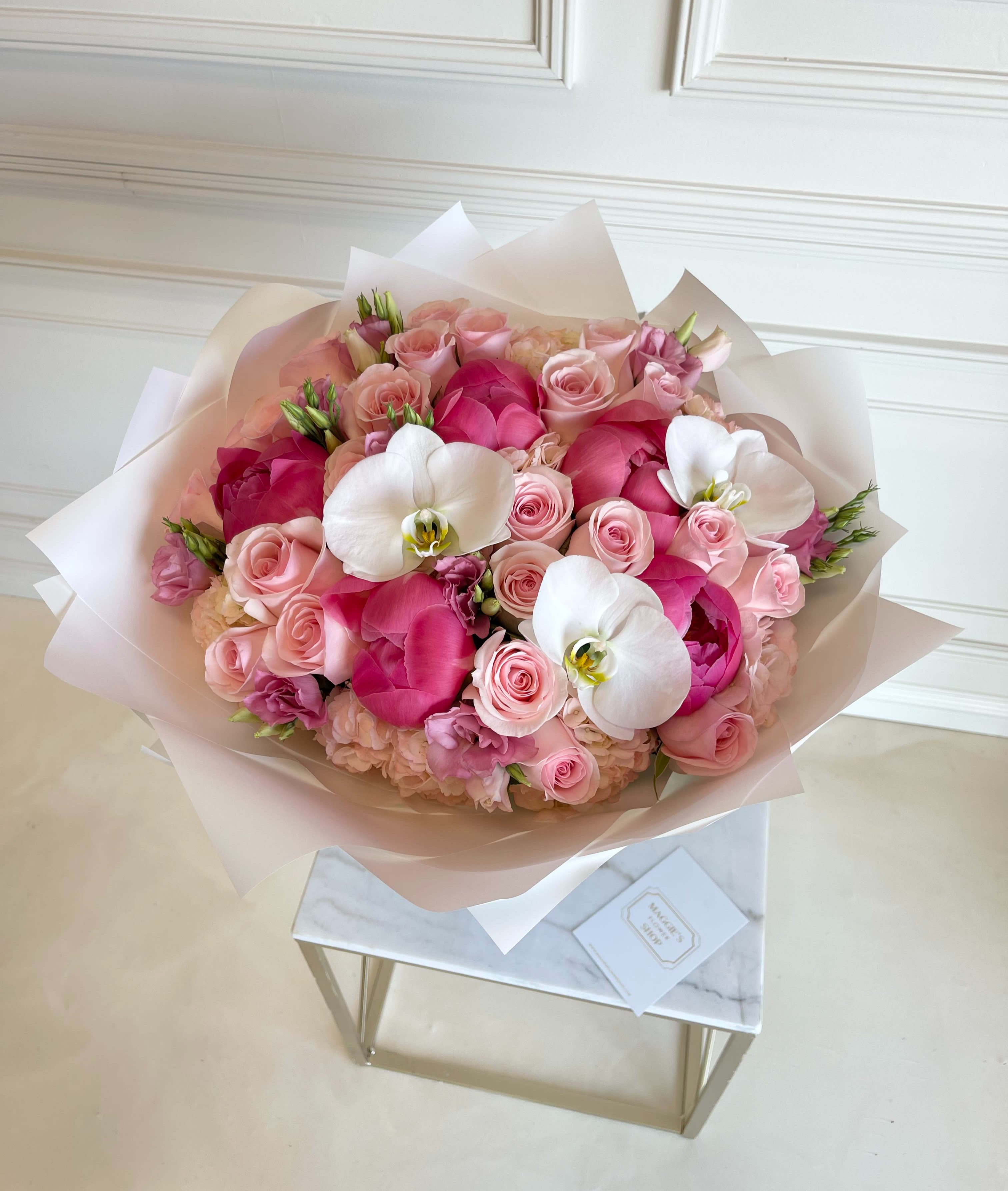 Pink rose bouquet with white orchids wrapped in pale paper