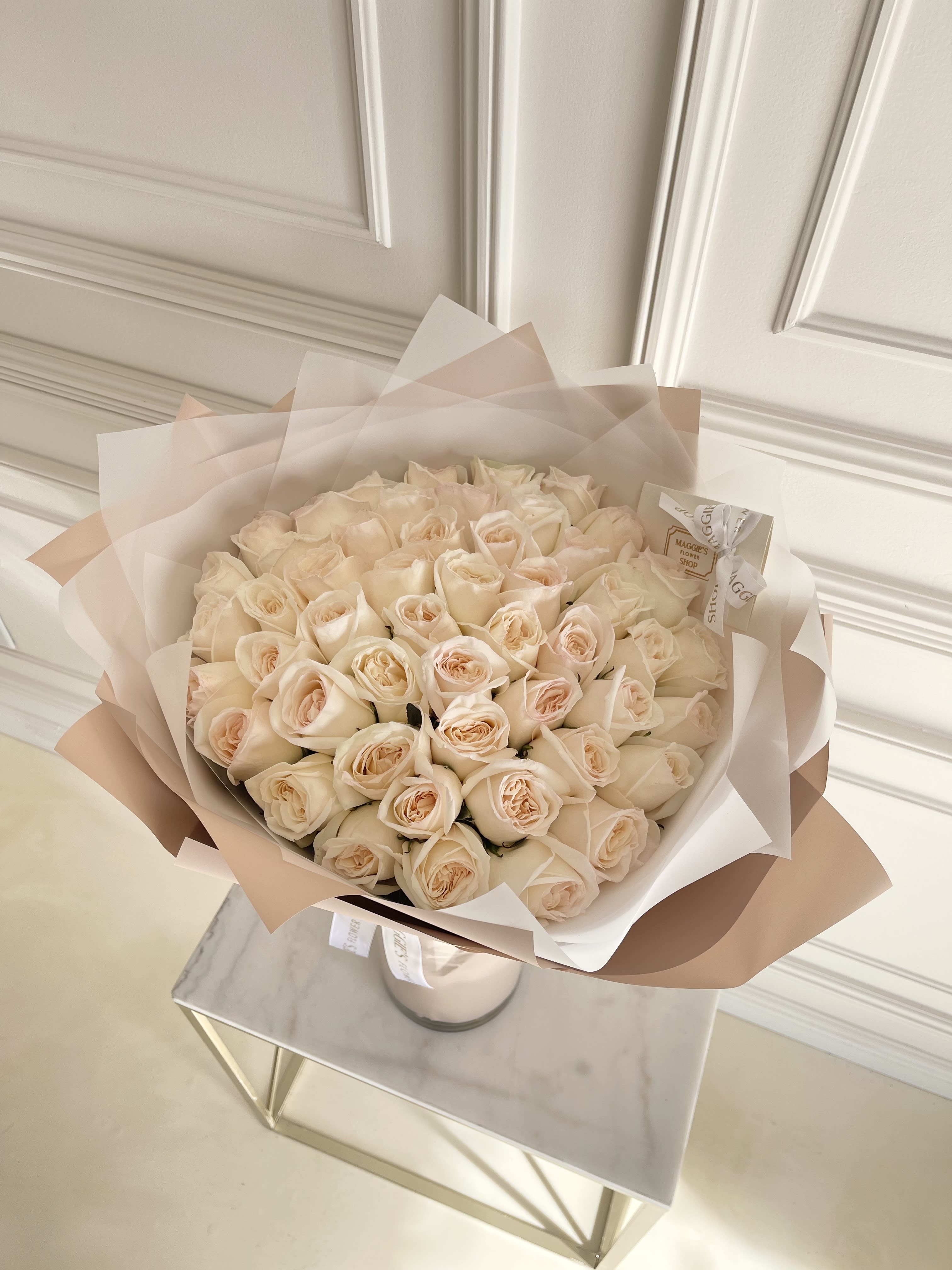 Bouquet of pale cream roses wrapped in blush paper