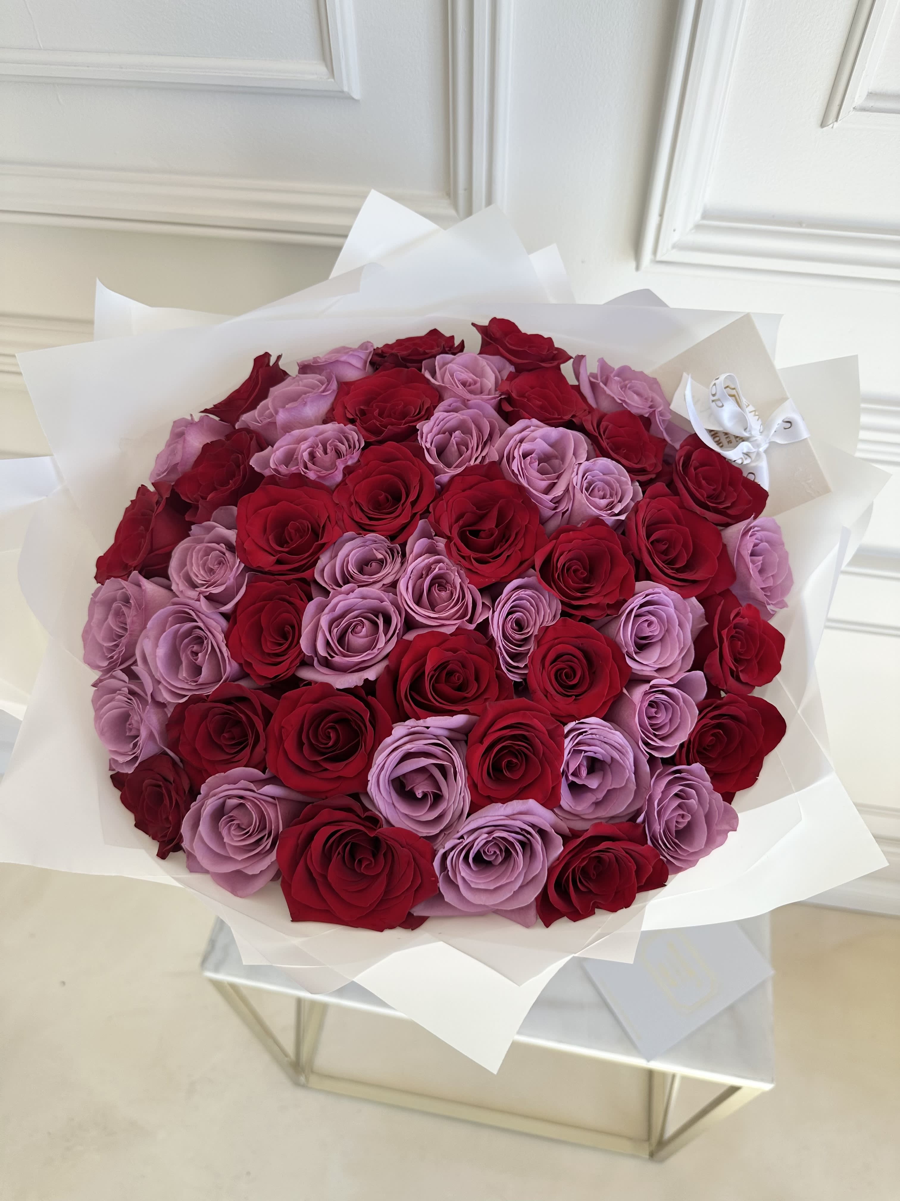 Bouquet of red and lavender roses wrapped in white paper