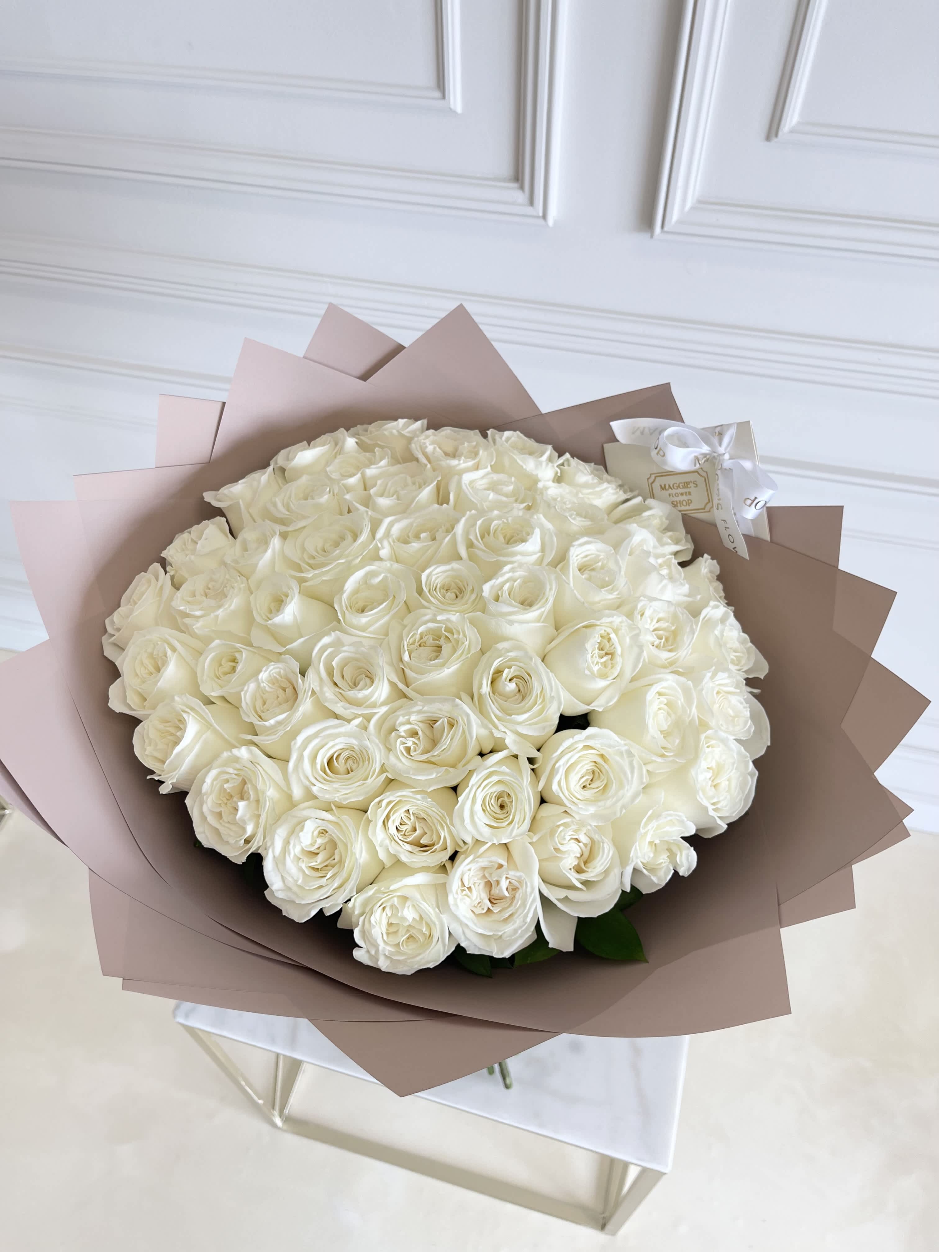 Large bouquet of white roses wrapped in blush paper