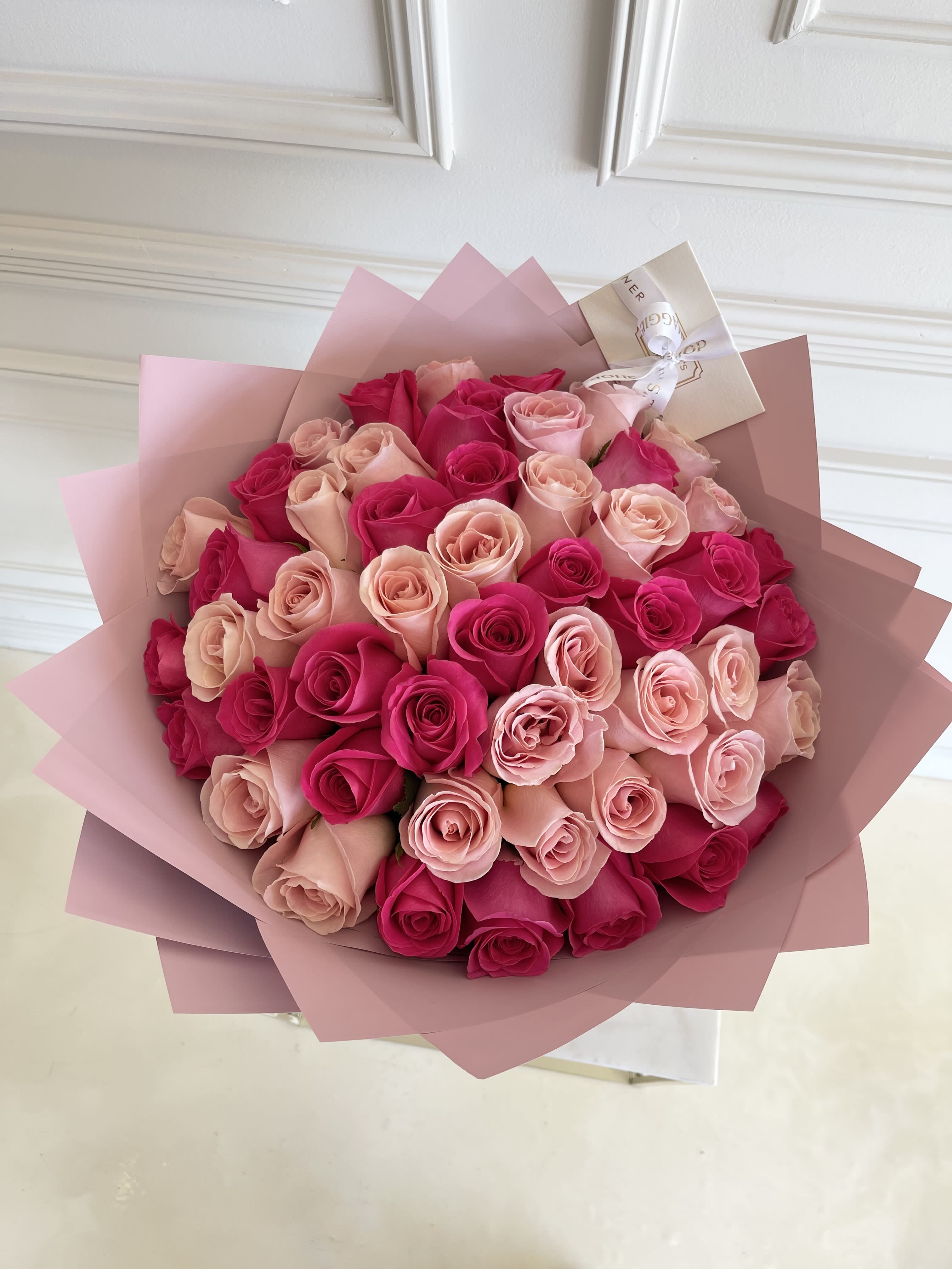 Bouquet of pink and hot pink roses wrapped in blush paper