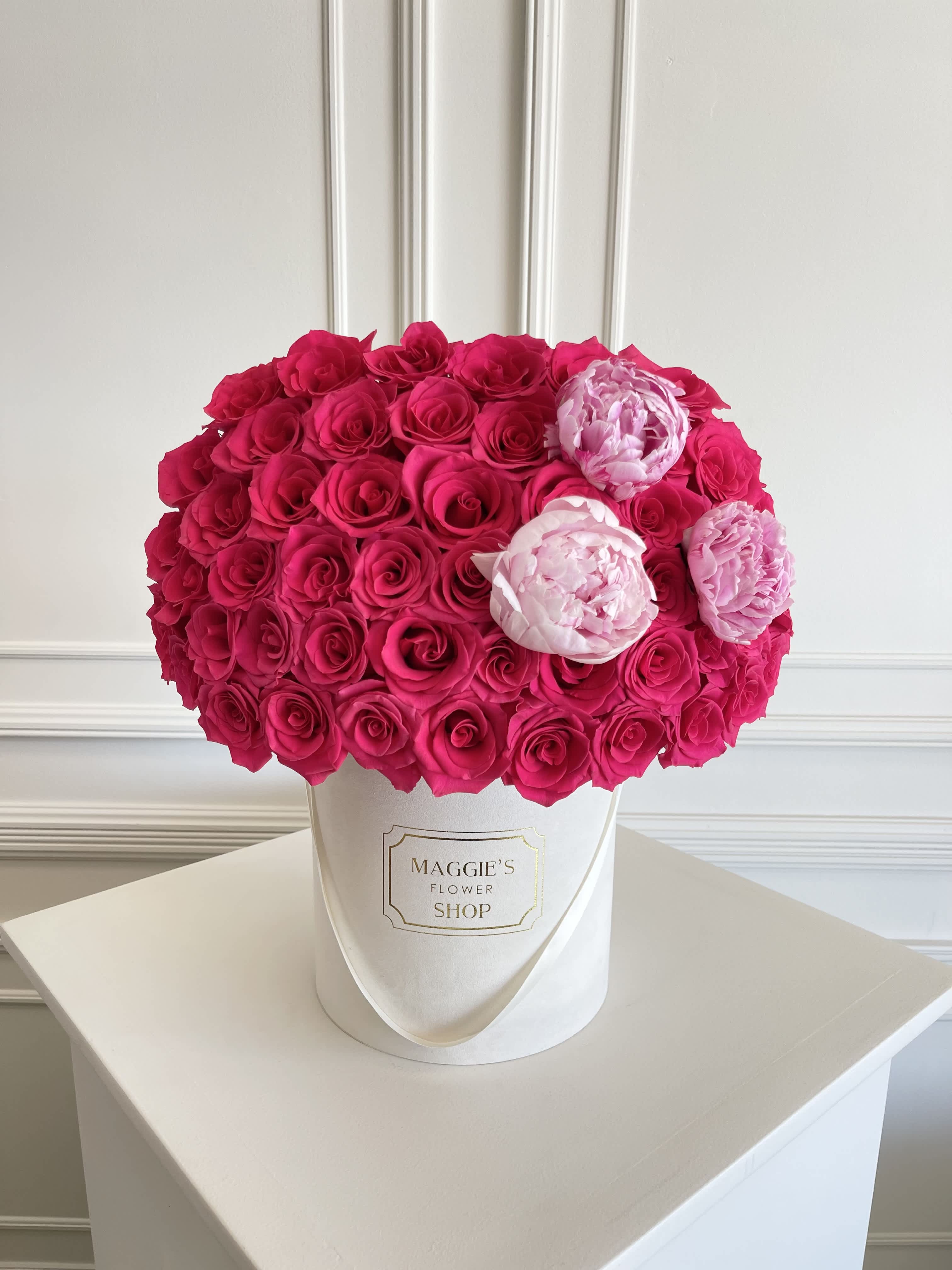 Hot pink and pale pink roses arranged in a white hat box