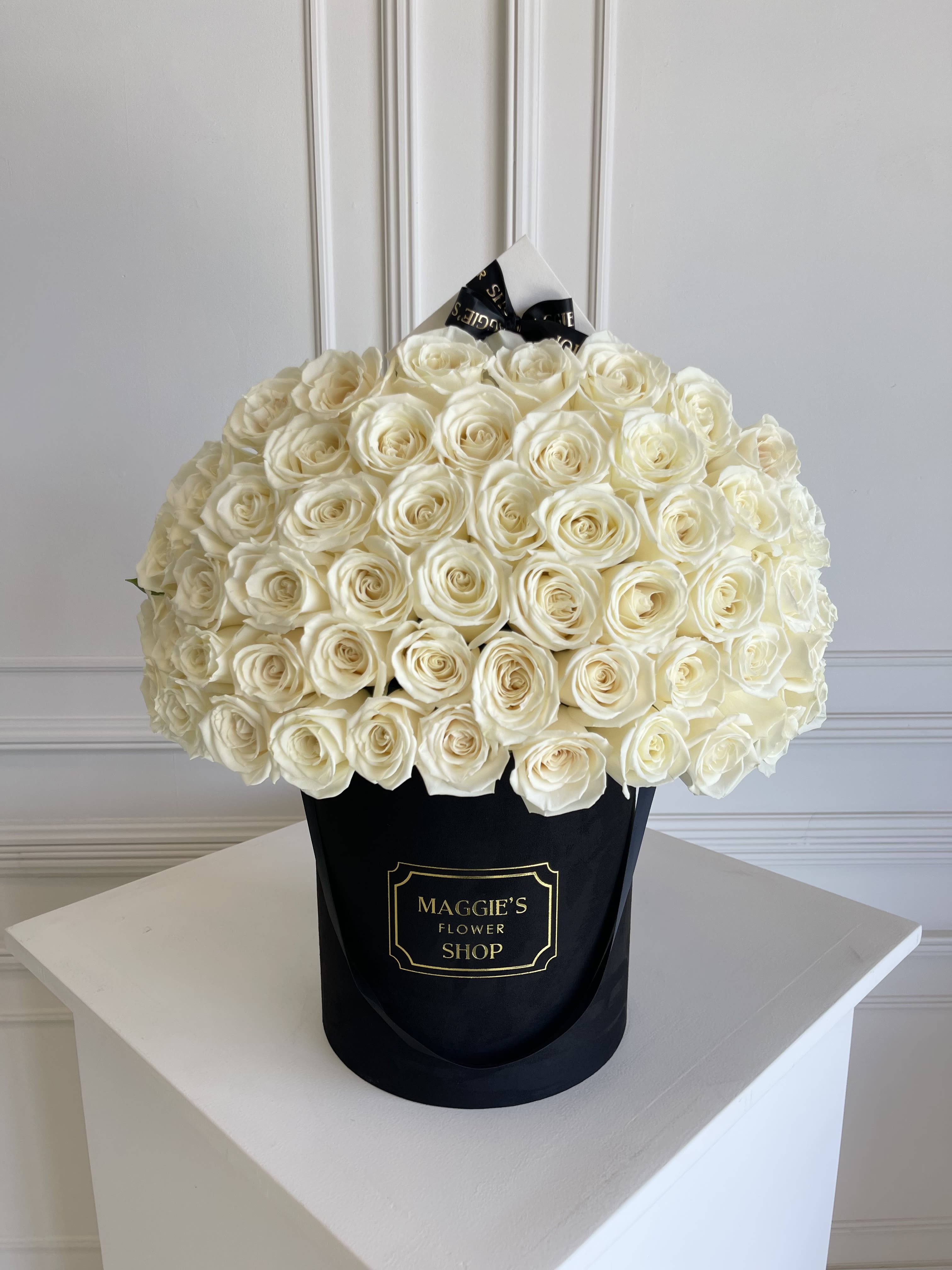 Large bouquet of white roses in a black hat box