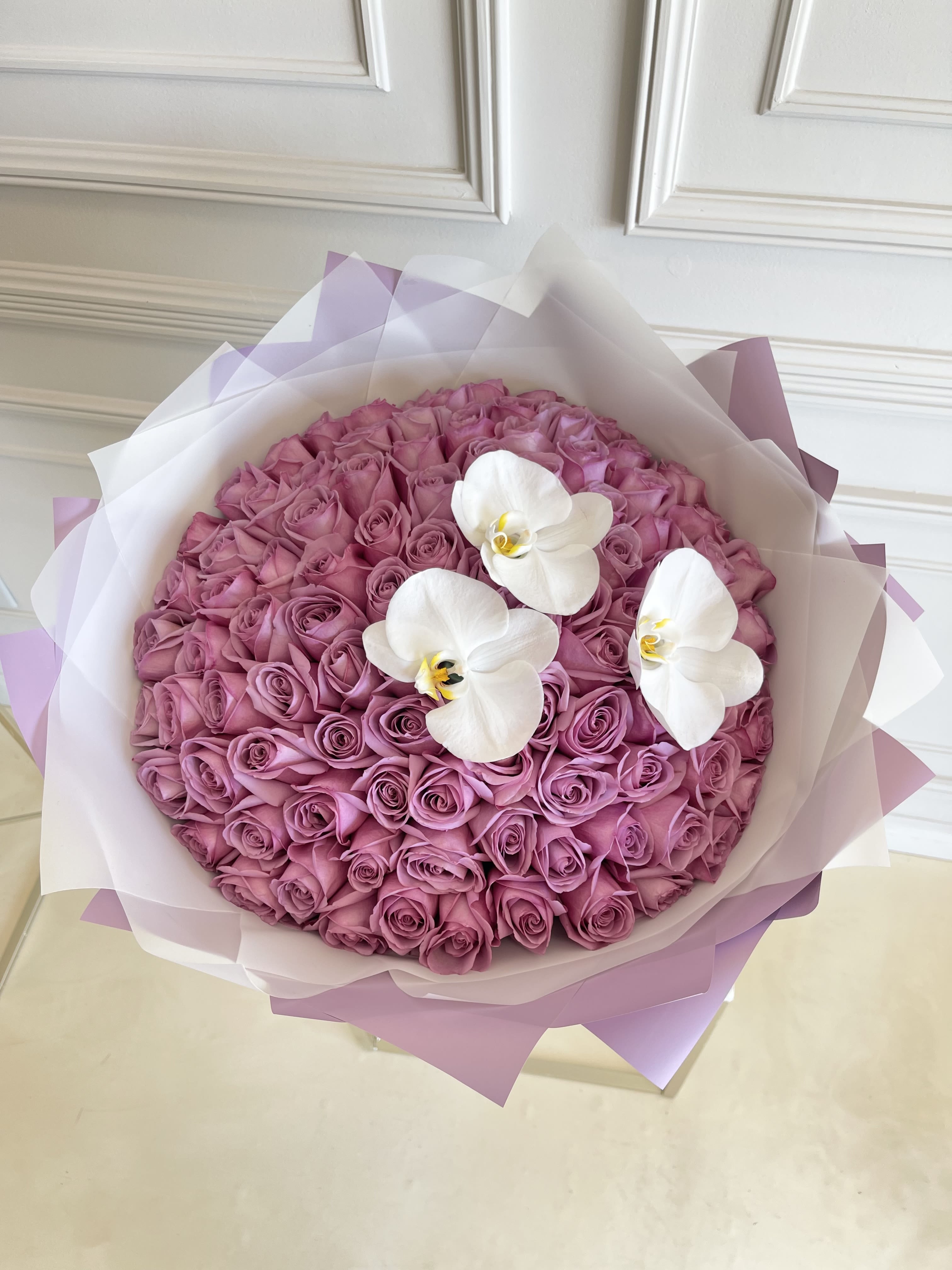 Round bouquet of pink roses with three white orchids