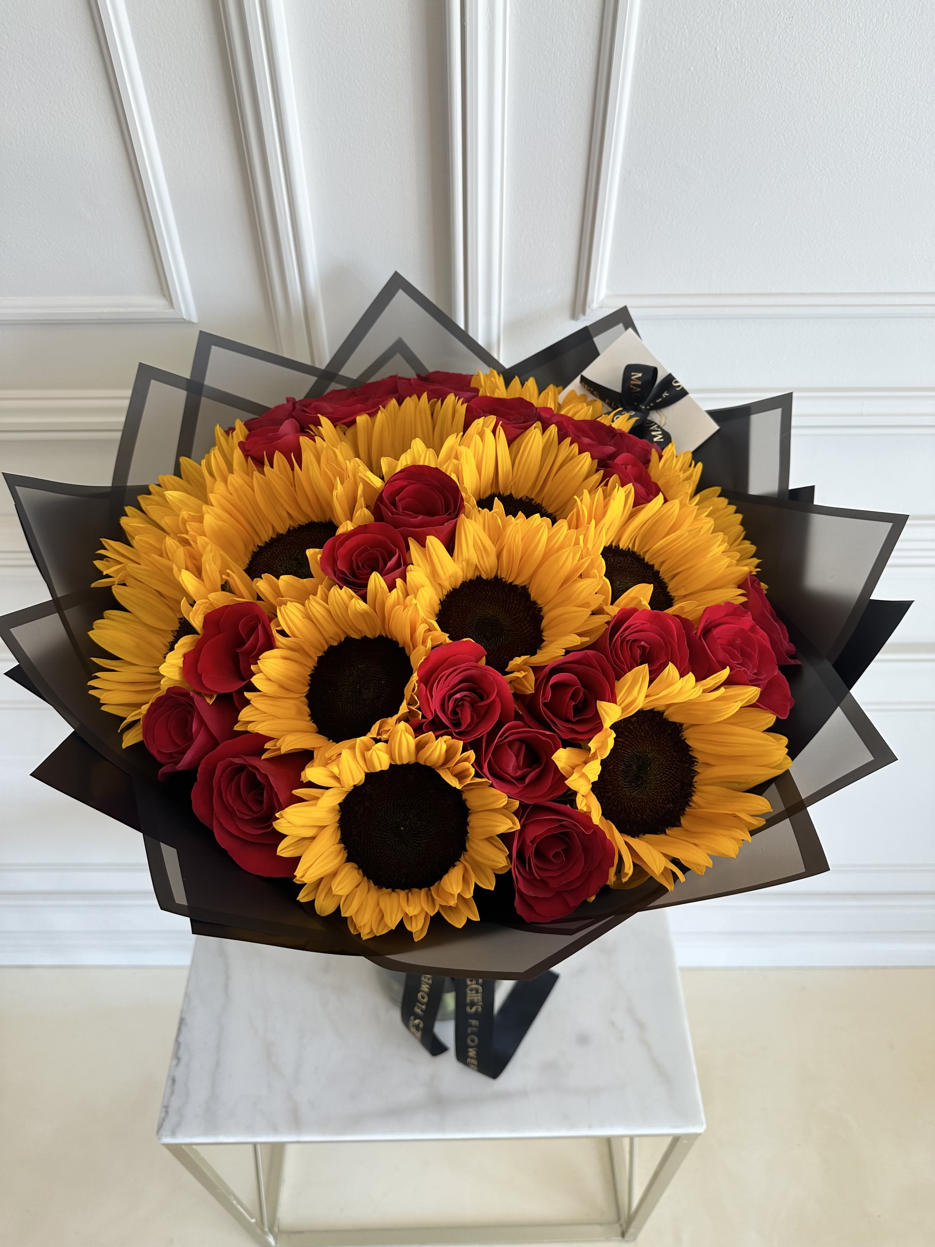 Bouquet of red roses and yellow sunflowers wrapped in black paper