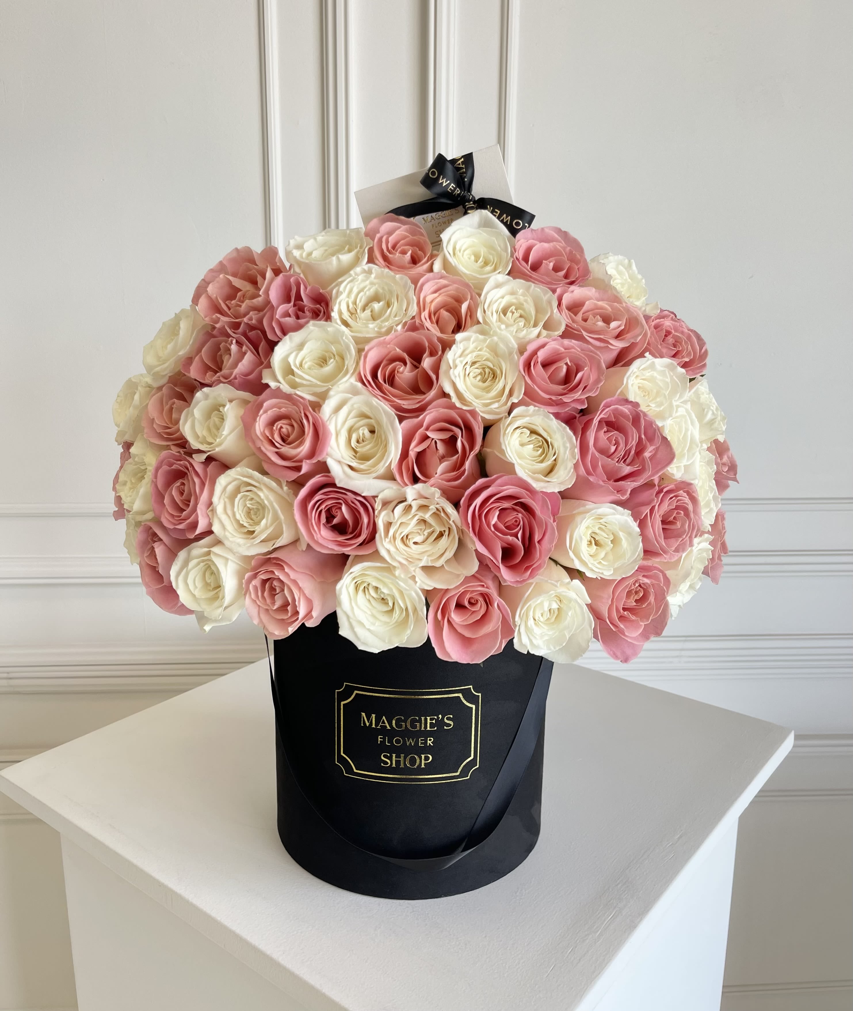 Bouquet of pink and white roses in a black hat box
