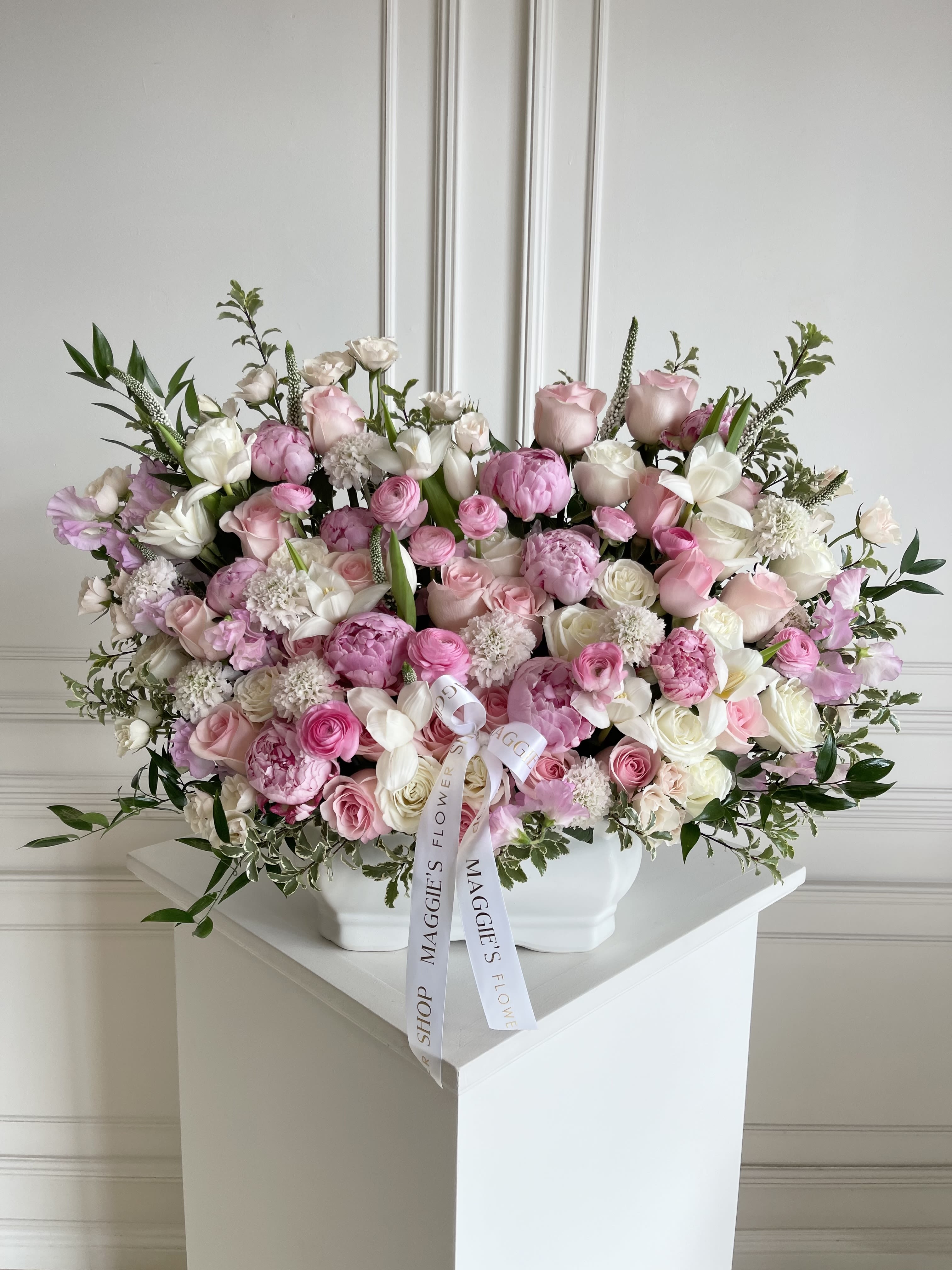 Large pink and white rose arrangement in a white vase