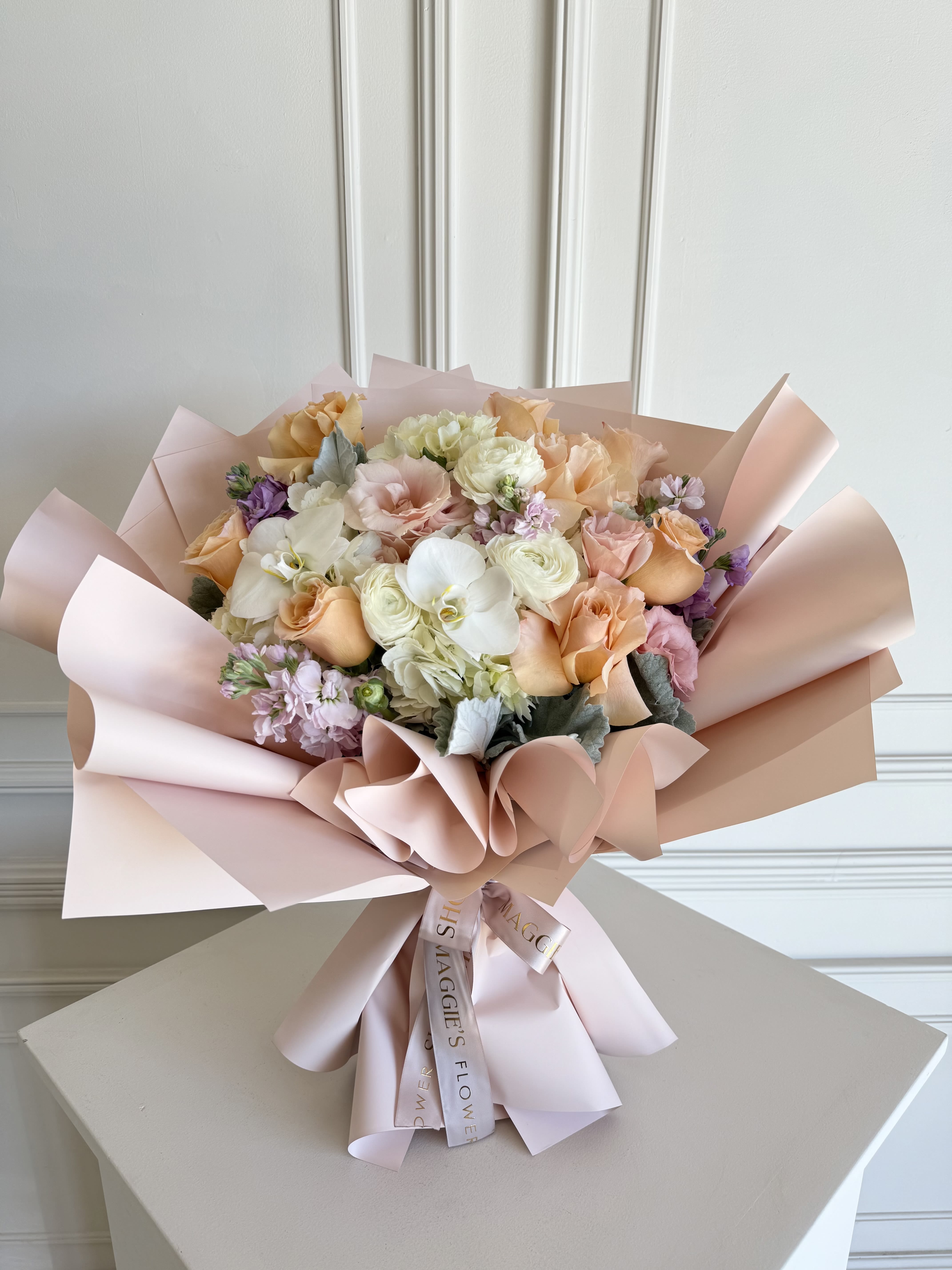 Bouquet of peach, pink, and white flowers wrapped in blush paper