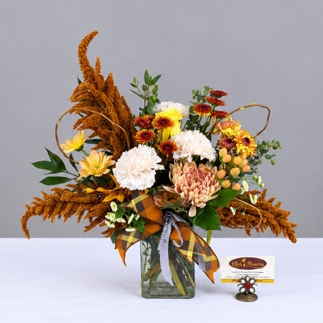 Autumn bouquet in a glass vase with mums, carnations, and orange filler flowers