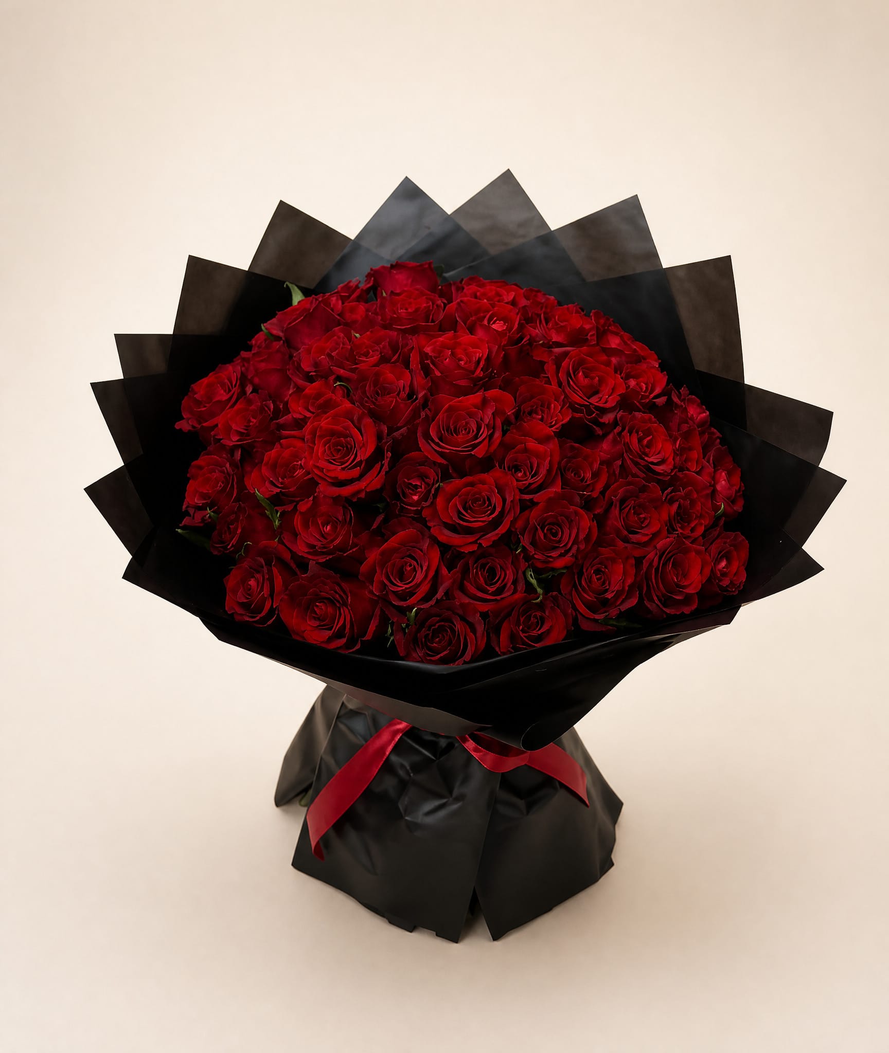 Large bouquet of red roses wrapped in black paper with a red ribbon