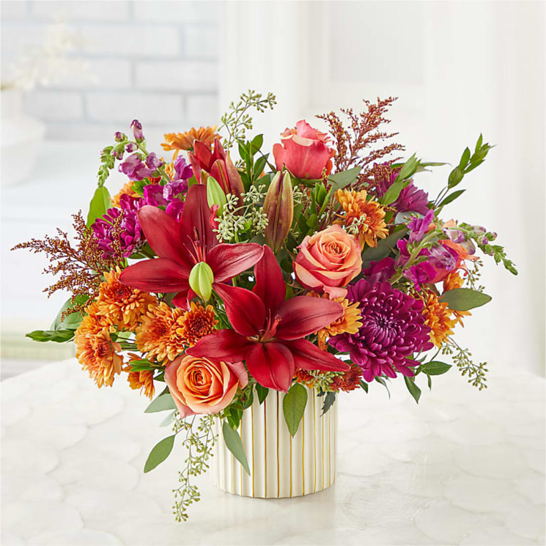 Colorful bouquet of lilies, roses, and mums in a striped vase