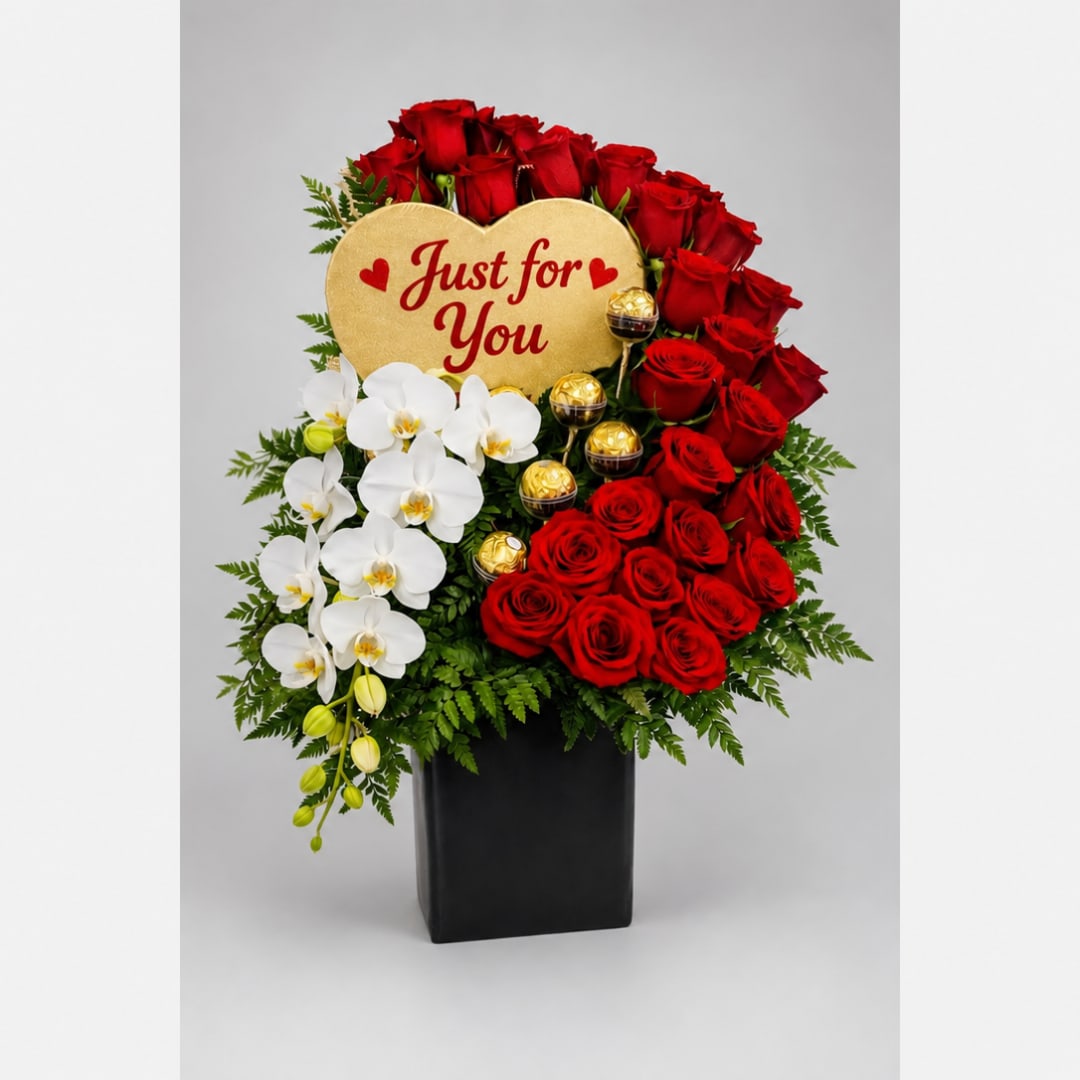 Red roses and white orchids in a black vase with a "Just for You" sign