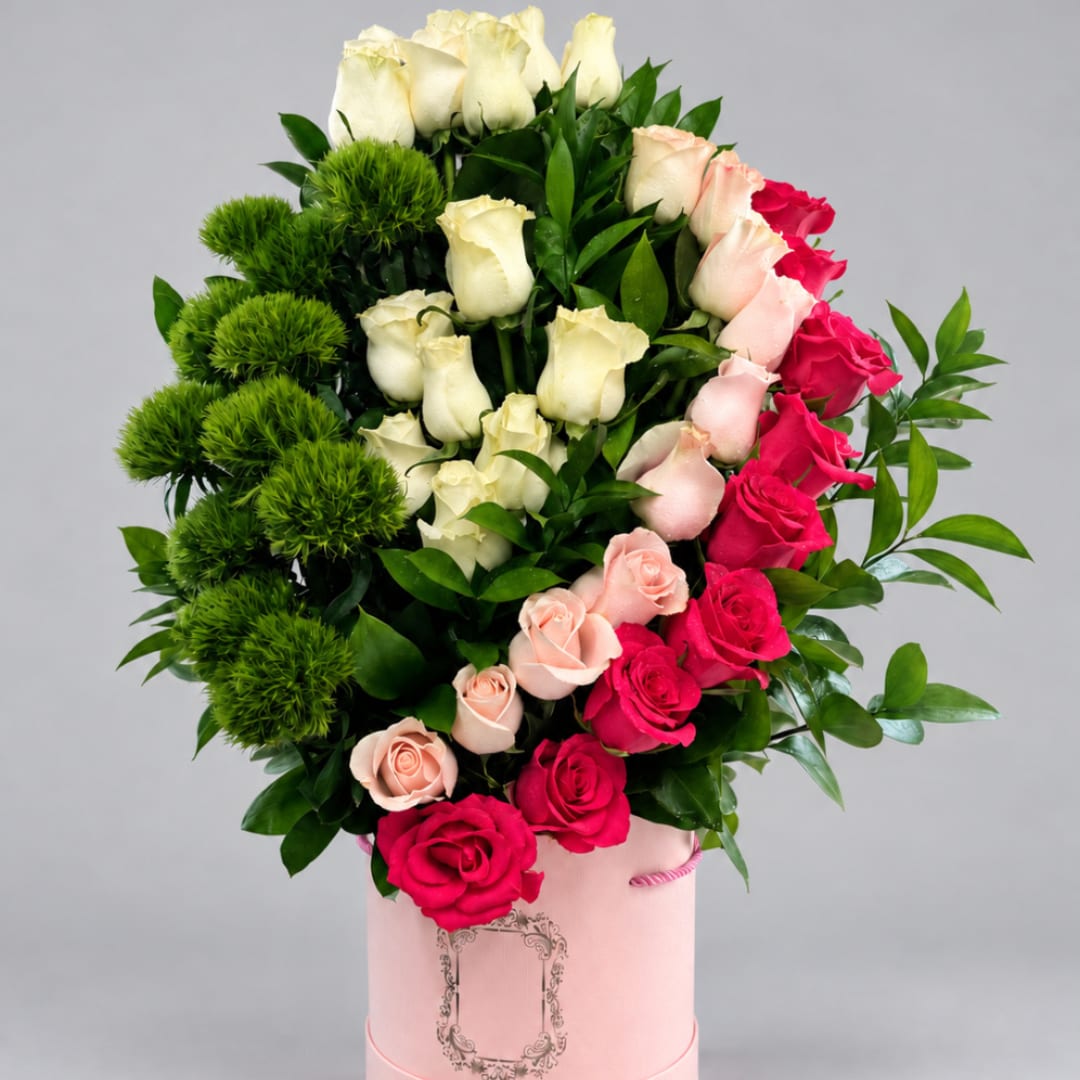 Pink and white roses arranged in a pink hatbox with green pom-pom accents