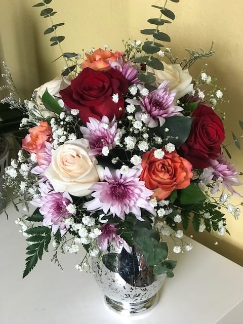 Bouquet of roses and purple daisies in a clear glass vase