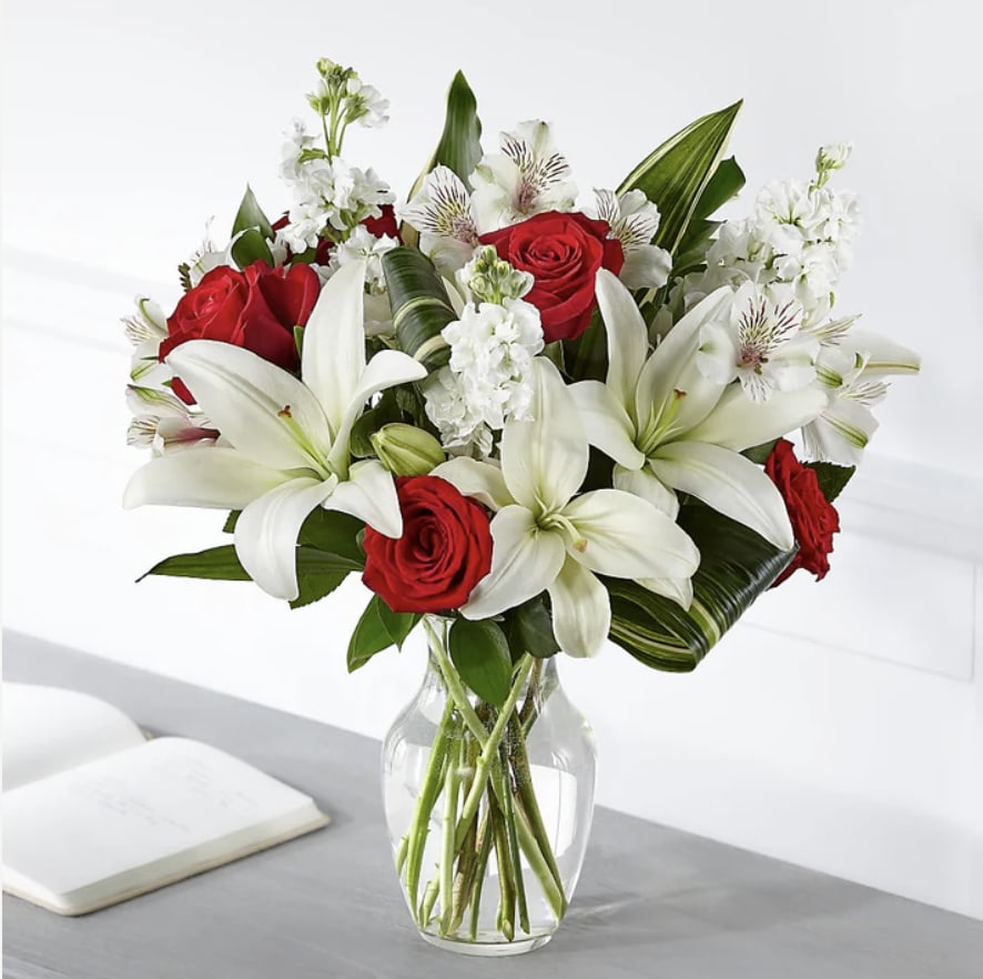 Red roses and white lilies arranged in a clear glass vase