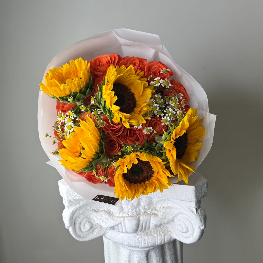 Bouquet of sunflowers and orange roses wrapped in white paper
