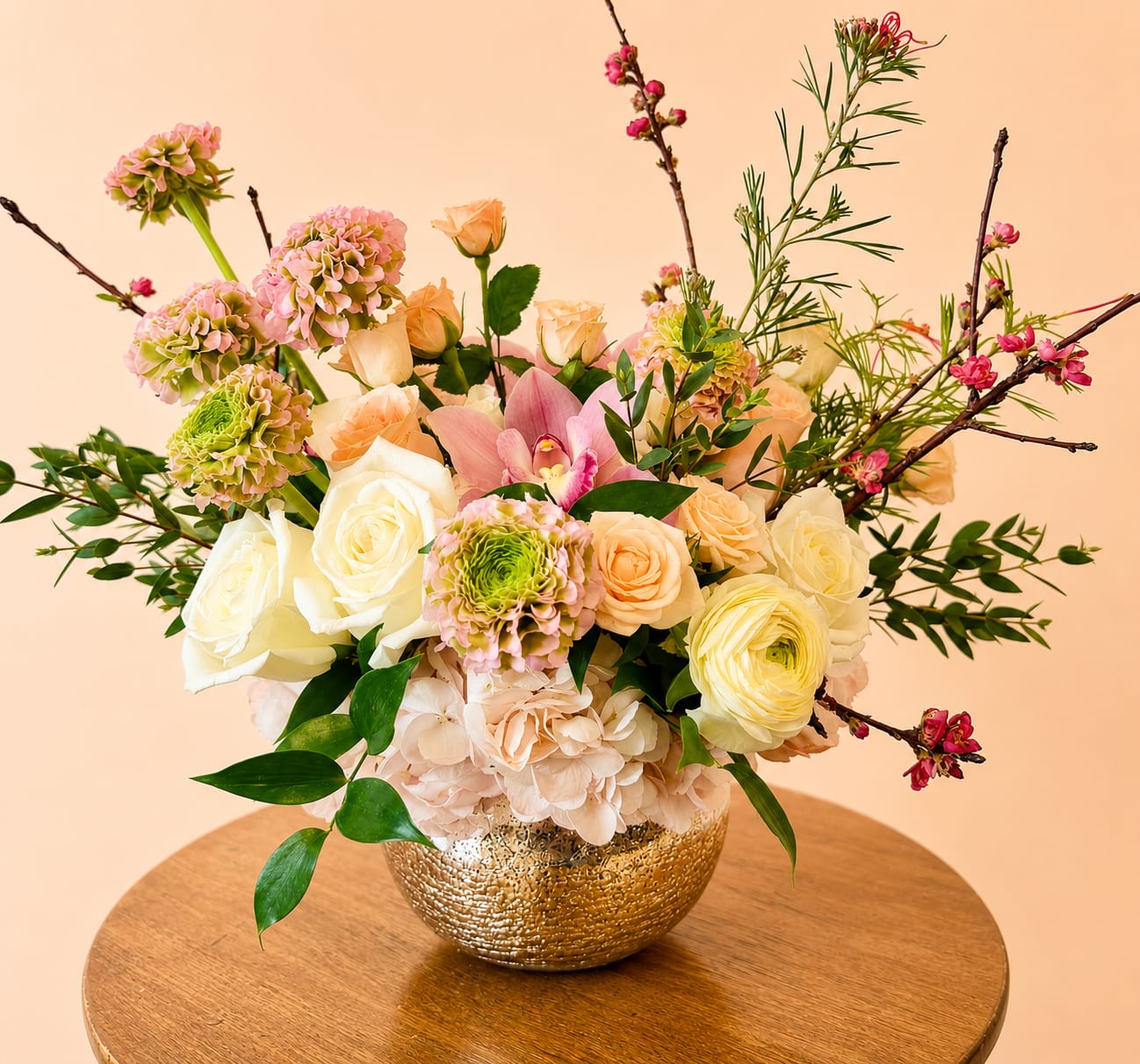 Mixed pastel flower arrangement in a gold bowl vase