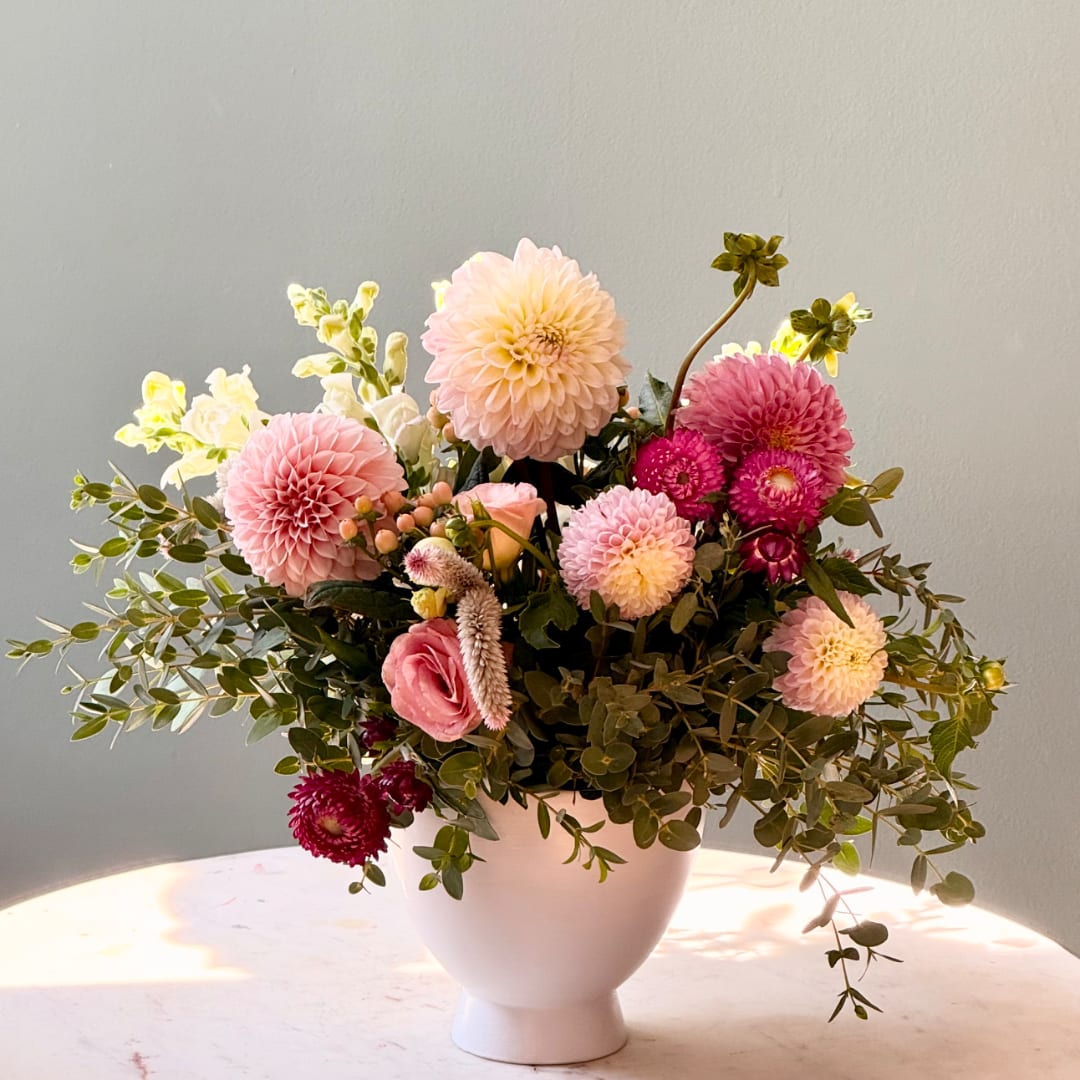 Pink and cream floral arrangement in a white vase