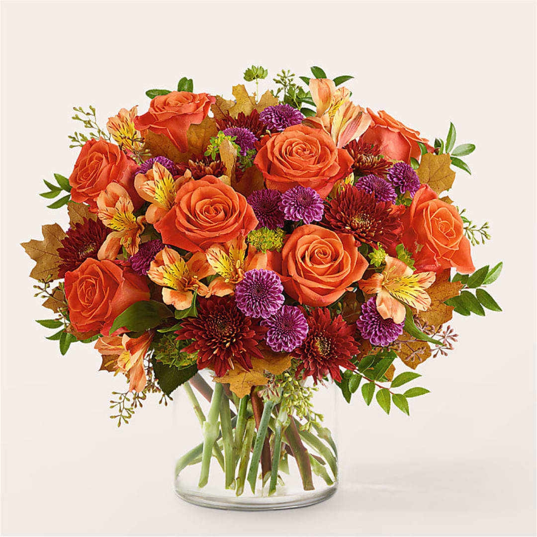 Orange roses and purple mums in a clear glass vase