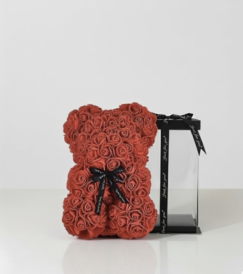 Red rose teddy bear beside a black gift box with ribbon