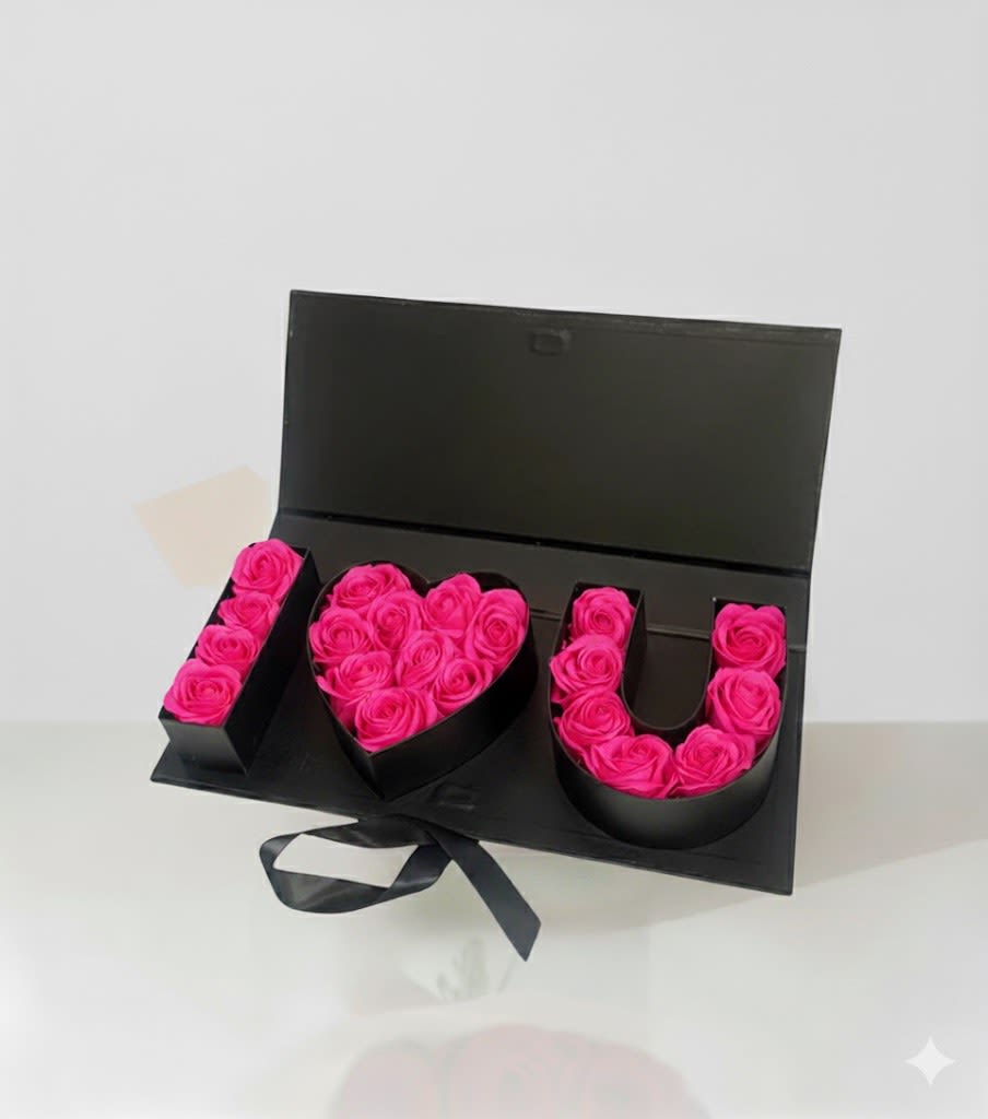Pink roses arranged in an open black box spelling "I ♥ U"
