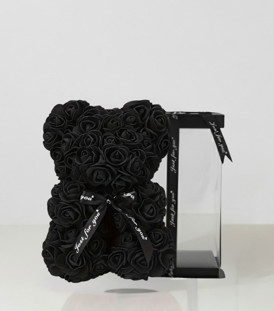 Black rose teddy bear beside a clear display box with ribbon