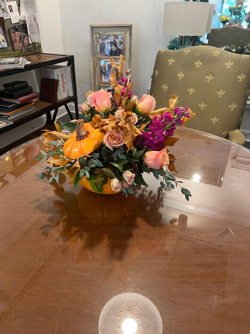 Pumpkin-shaped floral arrangement with peach roses and purple blooms