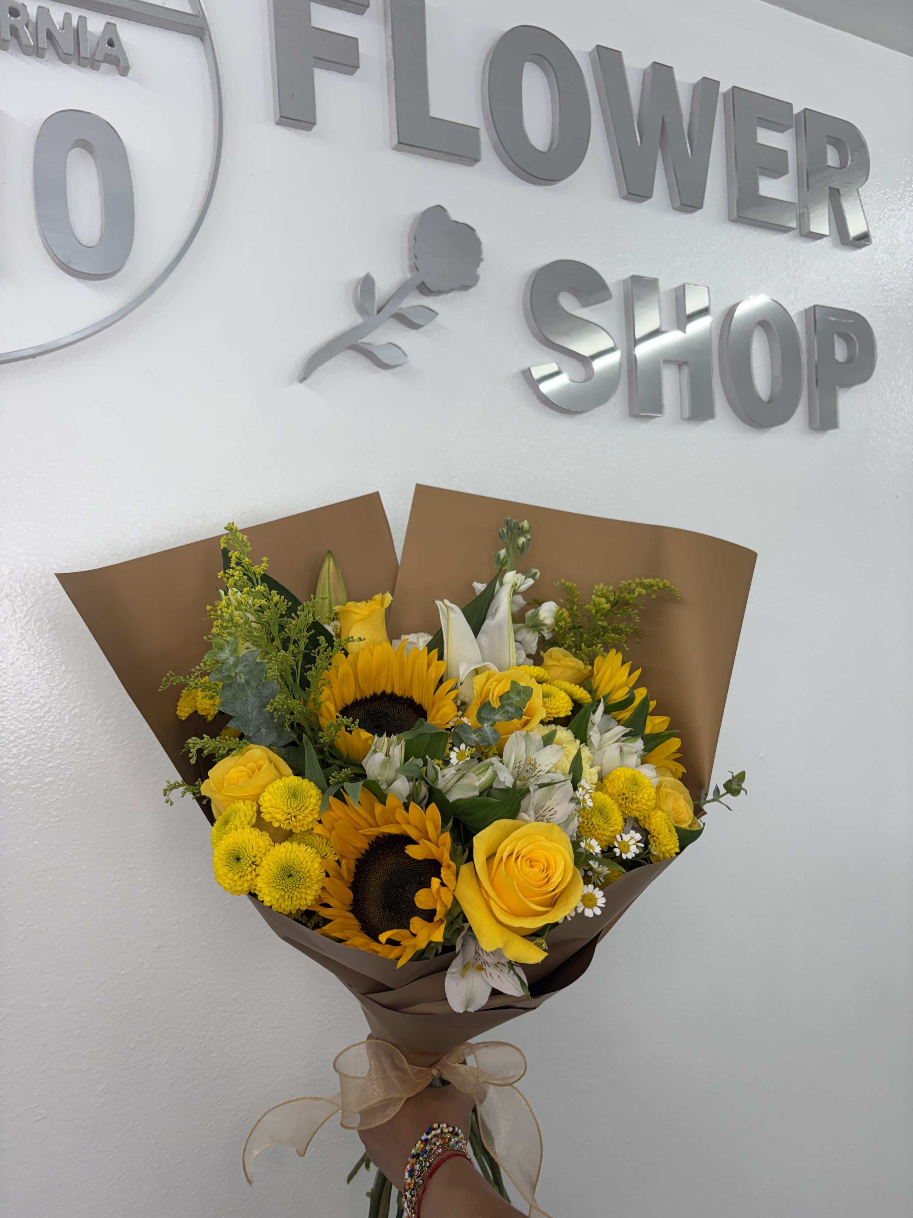 Yellow bouquet with sunflowers and roses wrapped in brown paper