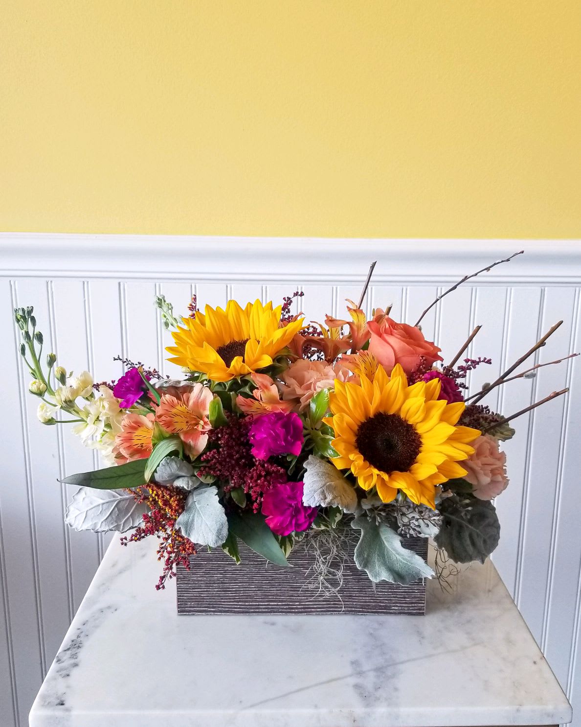 Mixed bouquet with sunflowers, peach roses, and magenta flowers in a rectangular box